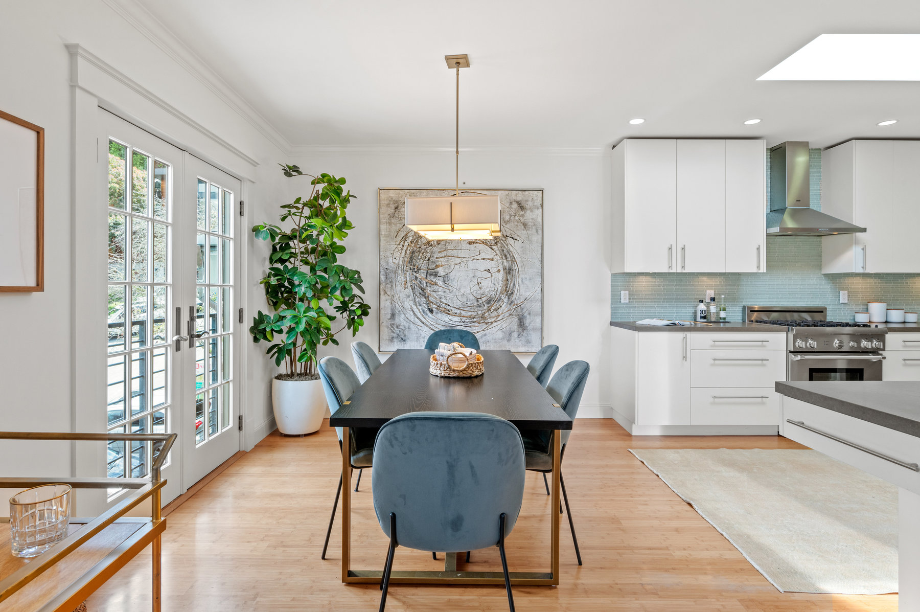 Looking at dining space from living room. Rectangular dining table that seats six. French doors to the left, kitchen to the right.