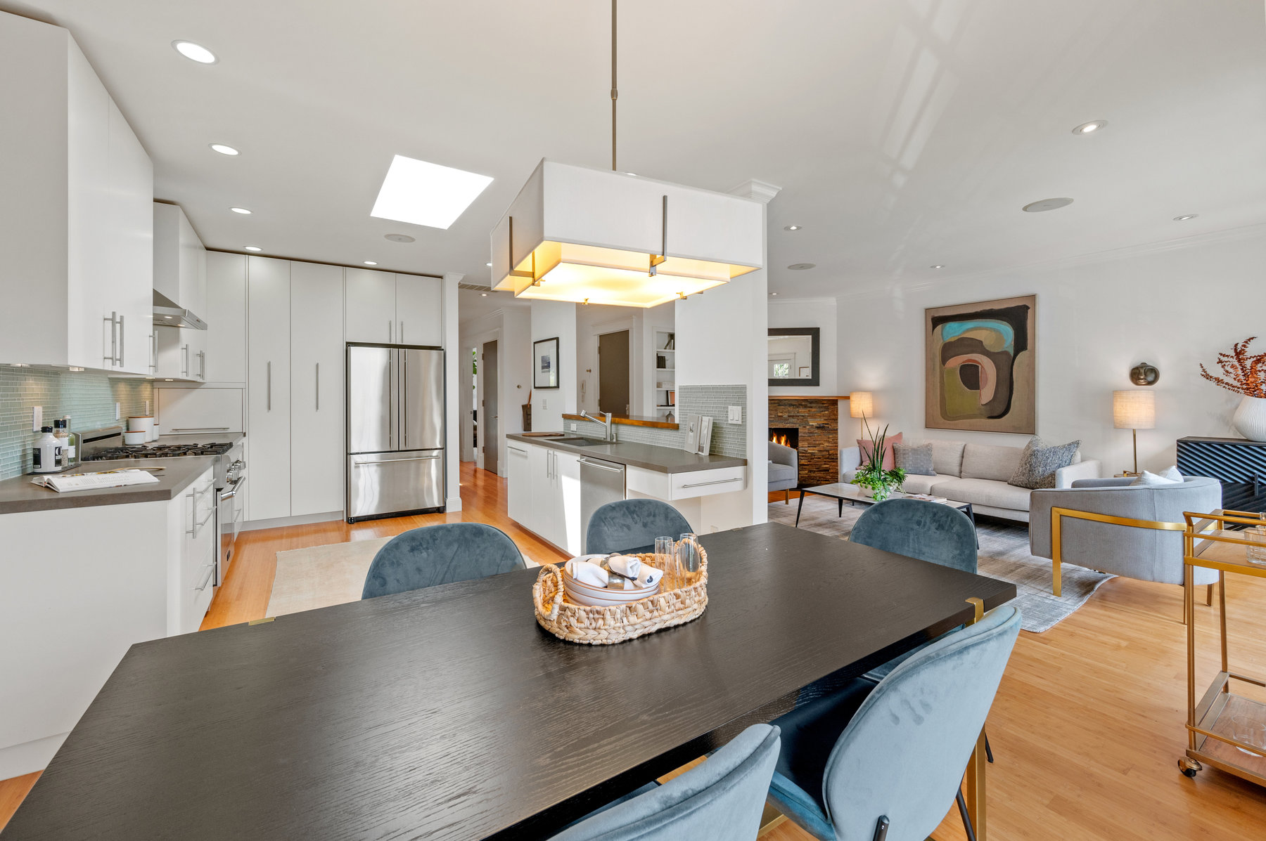 Looking over dining table from front corner of the room. Living room to right and kitchen to the left.