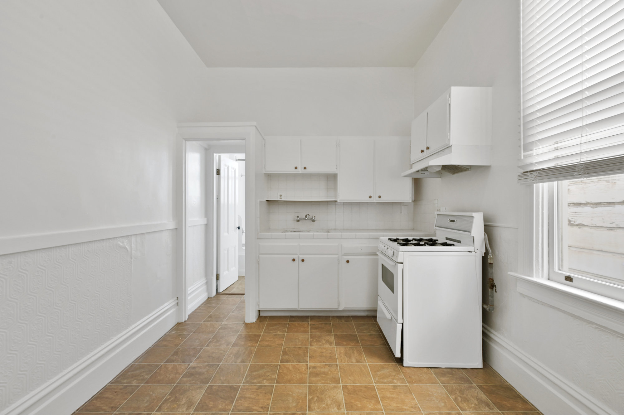 019022 Kitchen with white cabinets, showing a stove and window