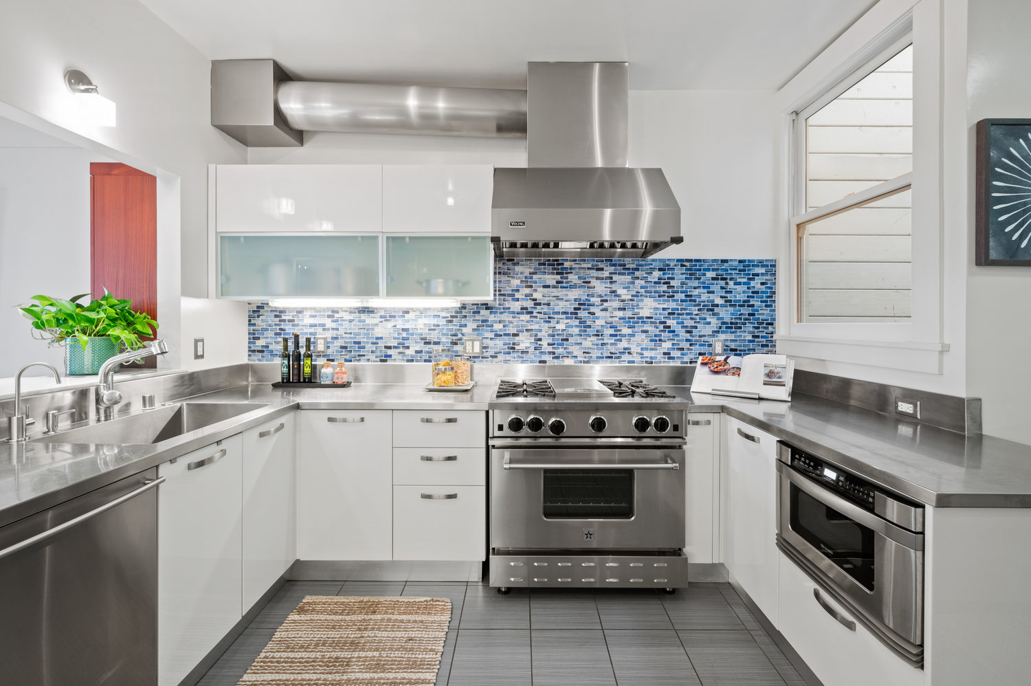 022photos41delmar022 Kitchen the has all stainless steel appliances and a beautiful light blue tile backsplash. .