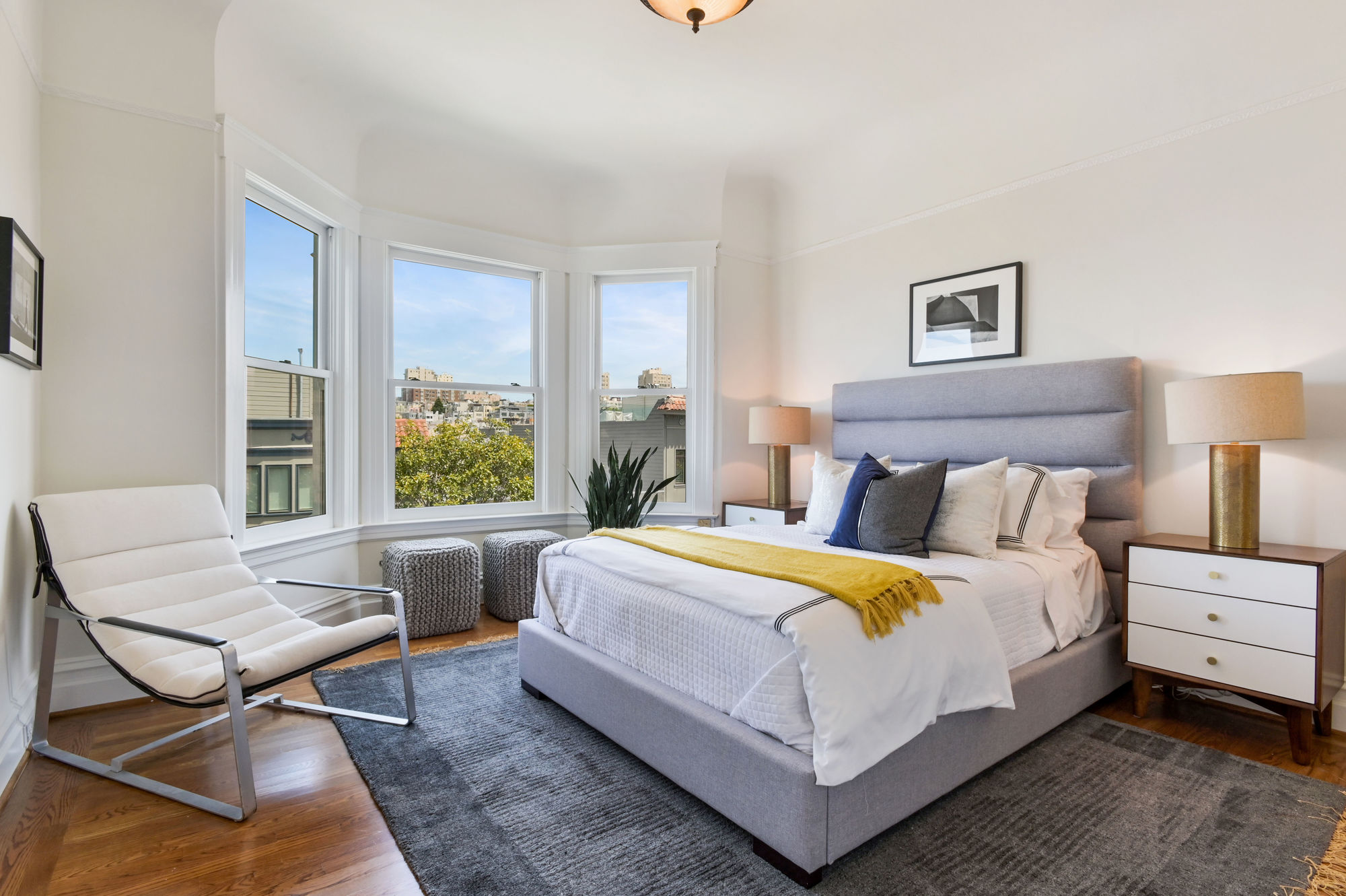 View of a large bedroom with bay windows and wood floors