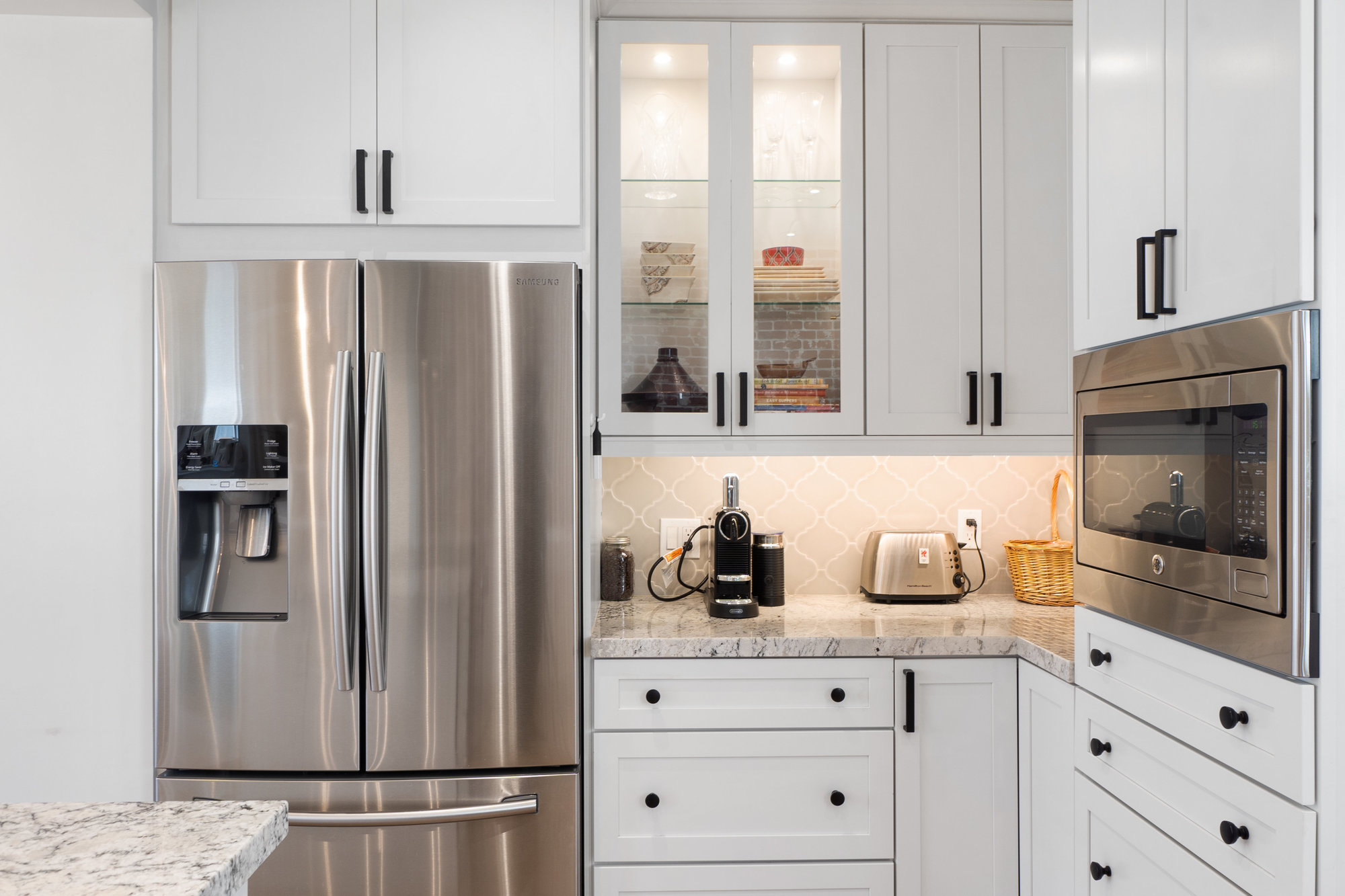 030031 View of the stainless steel refrigerator, and glass fronted upper cabinet