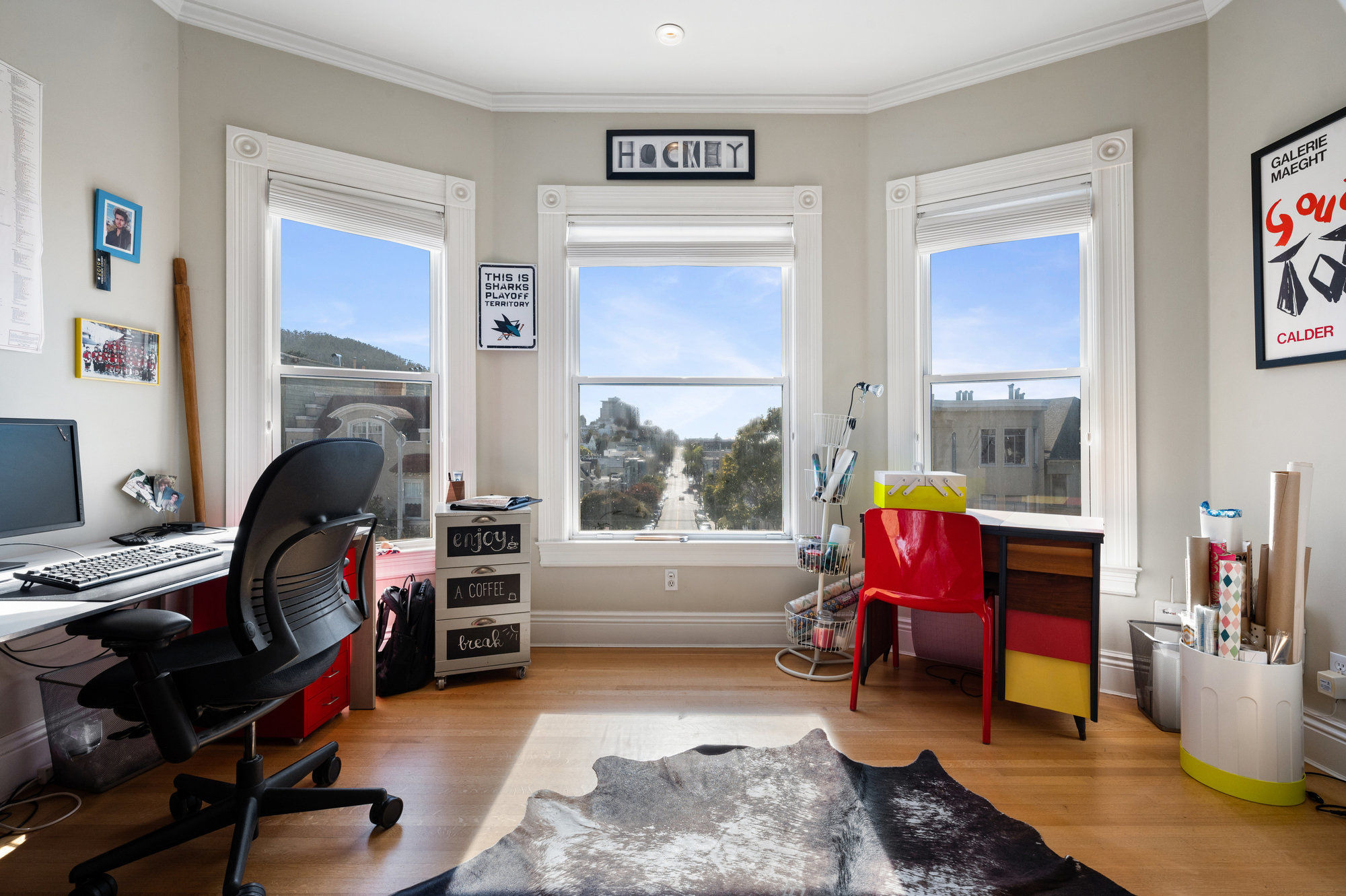 View of a room used as an office, featuring bay windows