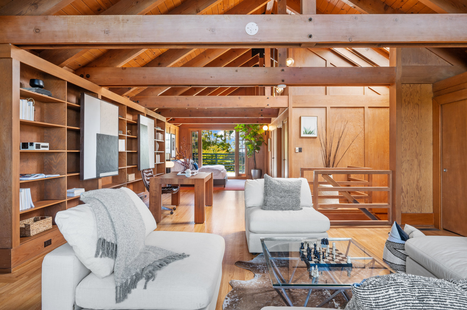Looking over sitting area in upper level.  You see over a wooden desk and bedroom area to the large french doors on the other side of the room.