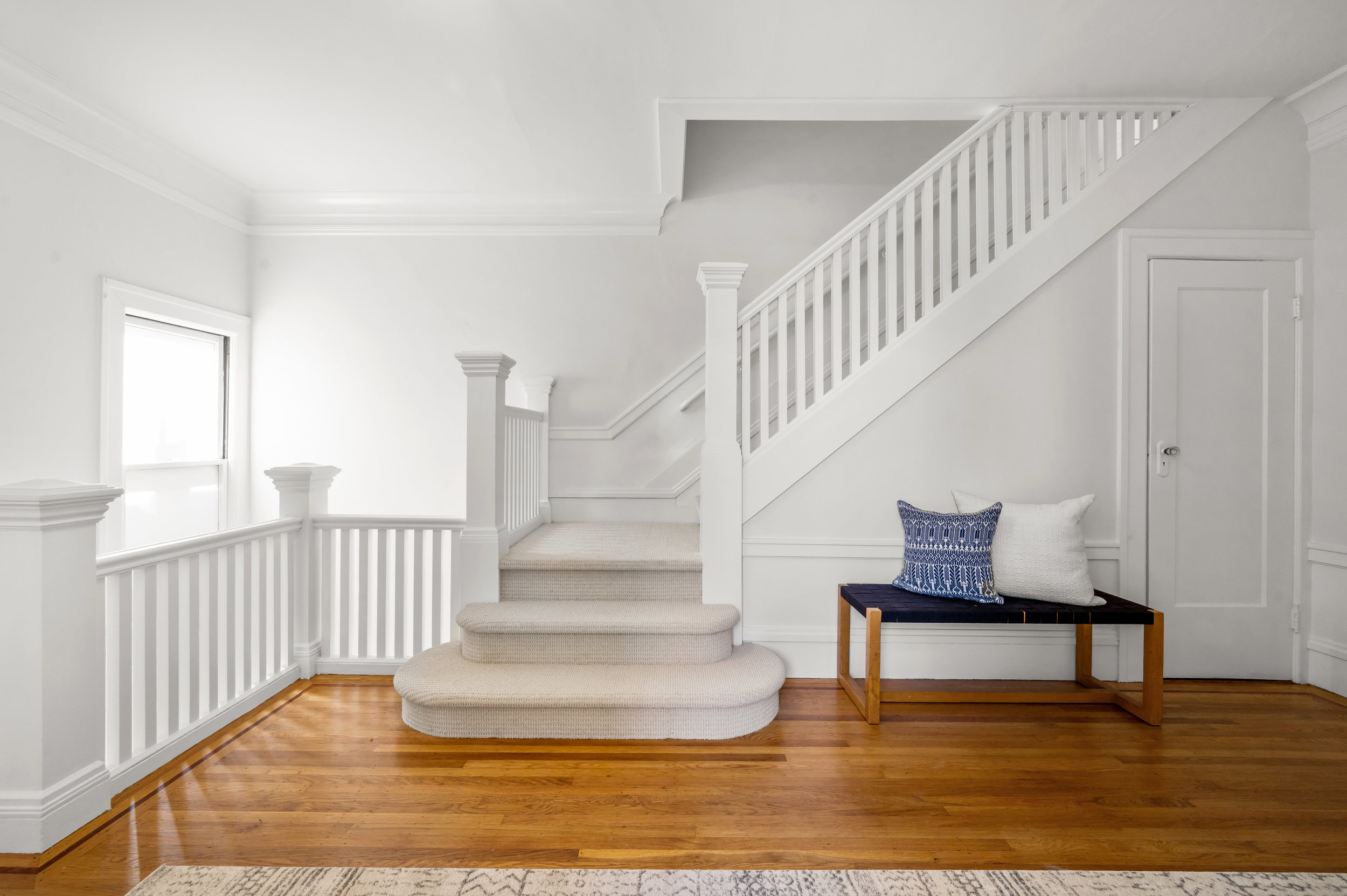 White wooden staircase leads upstairs