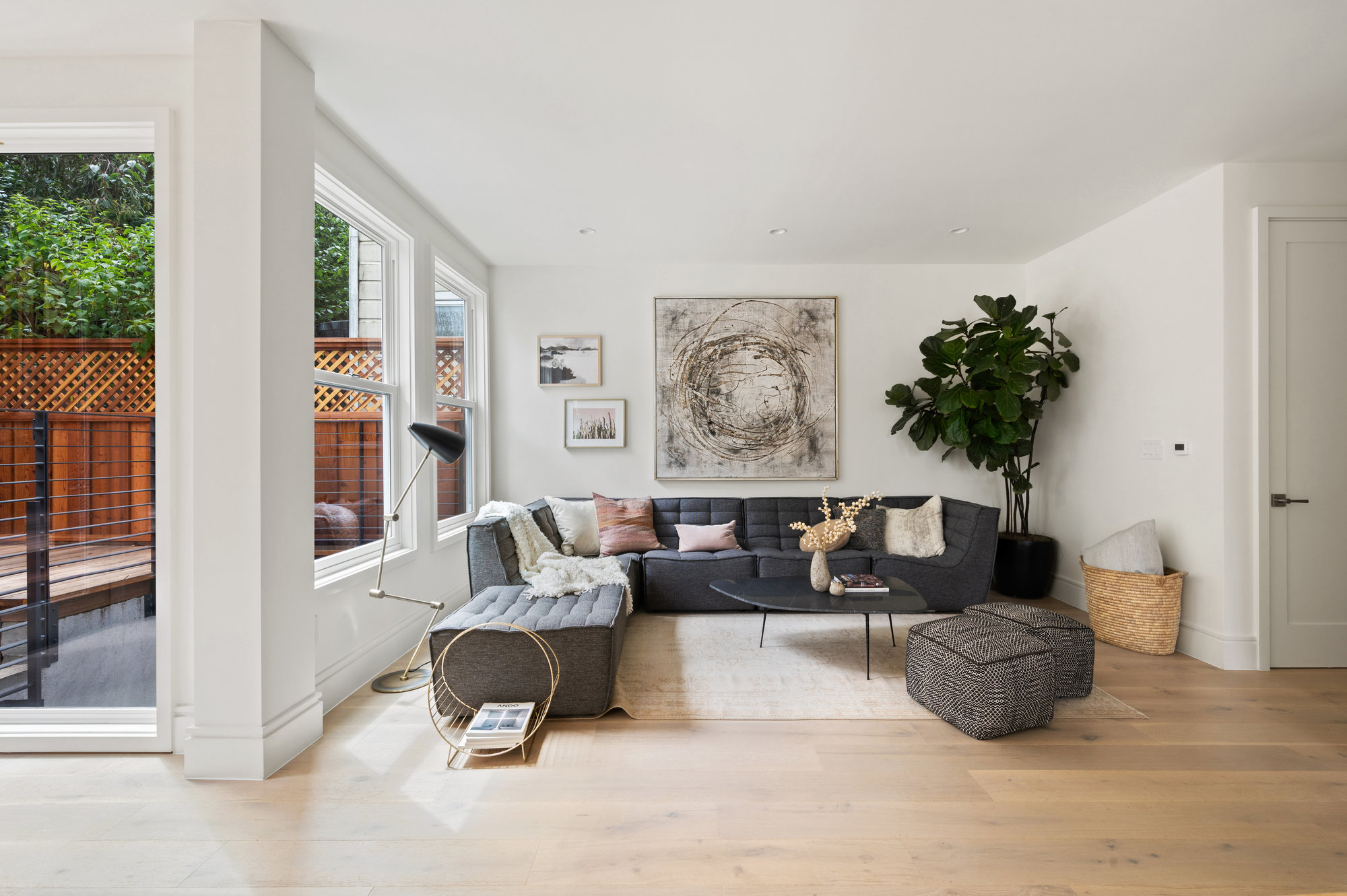 Highlighting the living room space.  Large windows looking out to back outdoor space. There is a large L shaped couch.