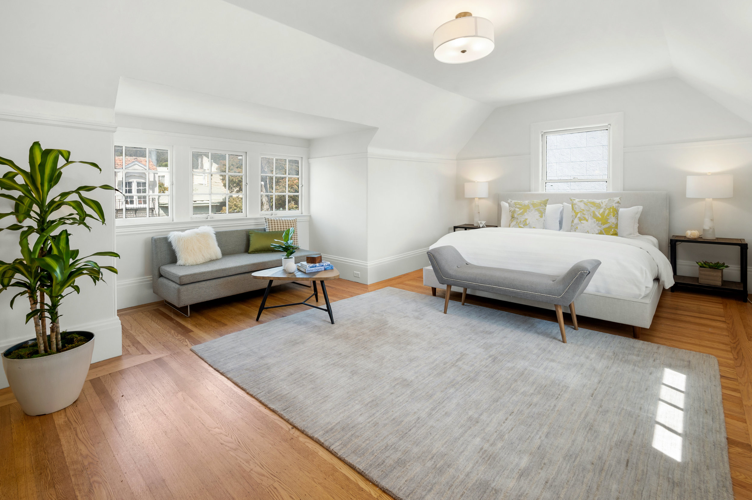 A luxury primary bedroom with wood floors and plenty of natural light