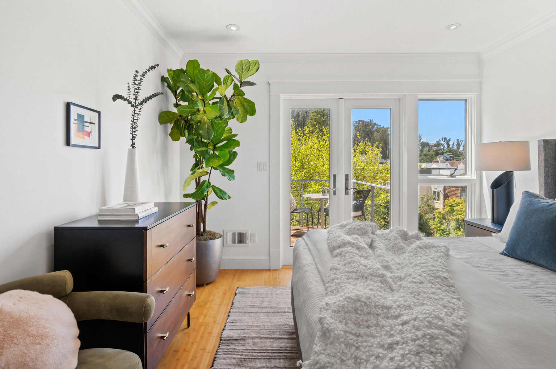 Looking over primary from closet. You can see a beautiful view through glass french doors.Lots of greenery.