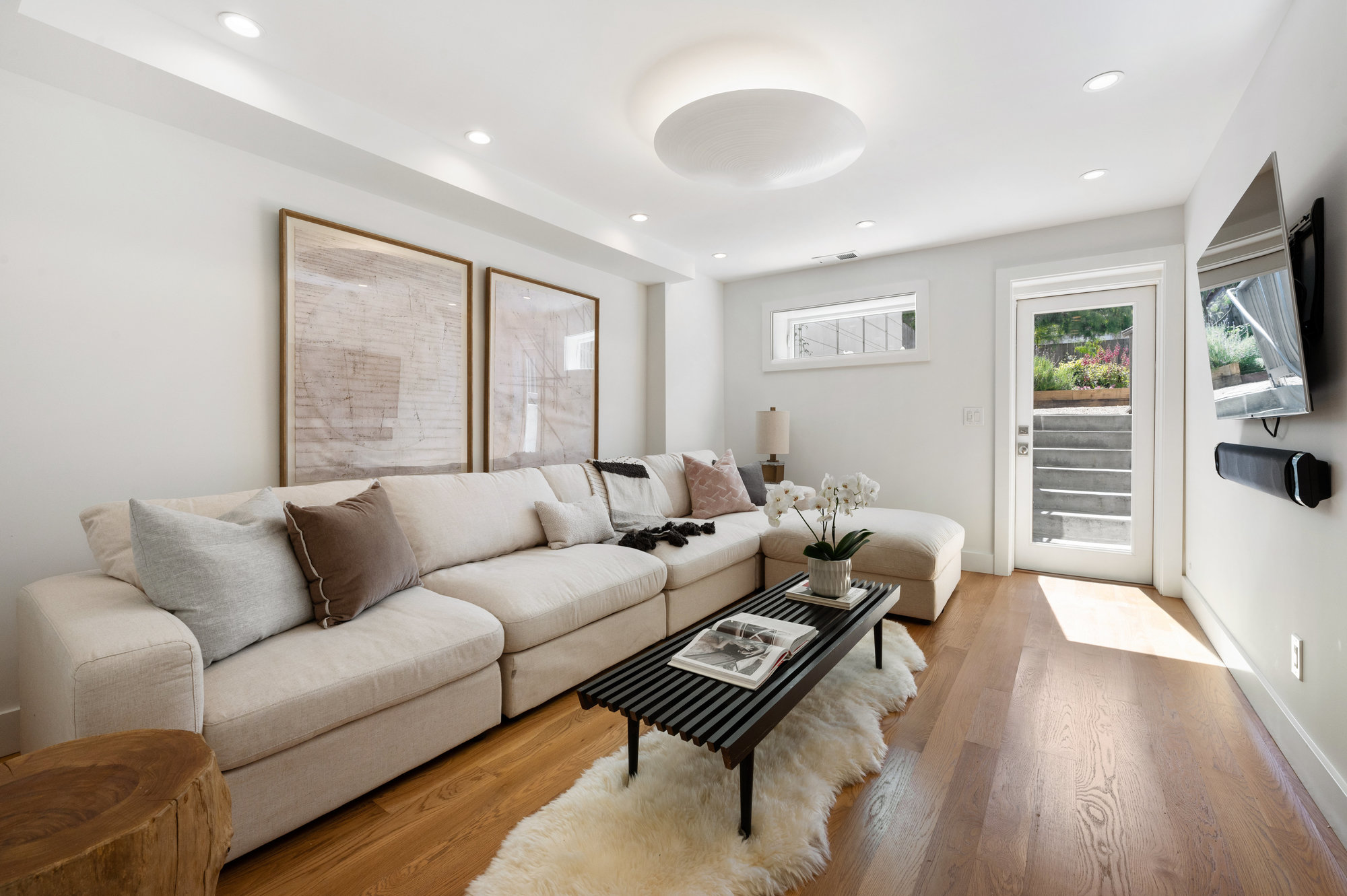View of the lower living space, featuring wood floors and a door to the rear yard