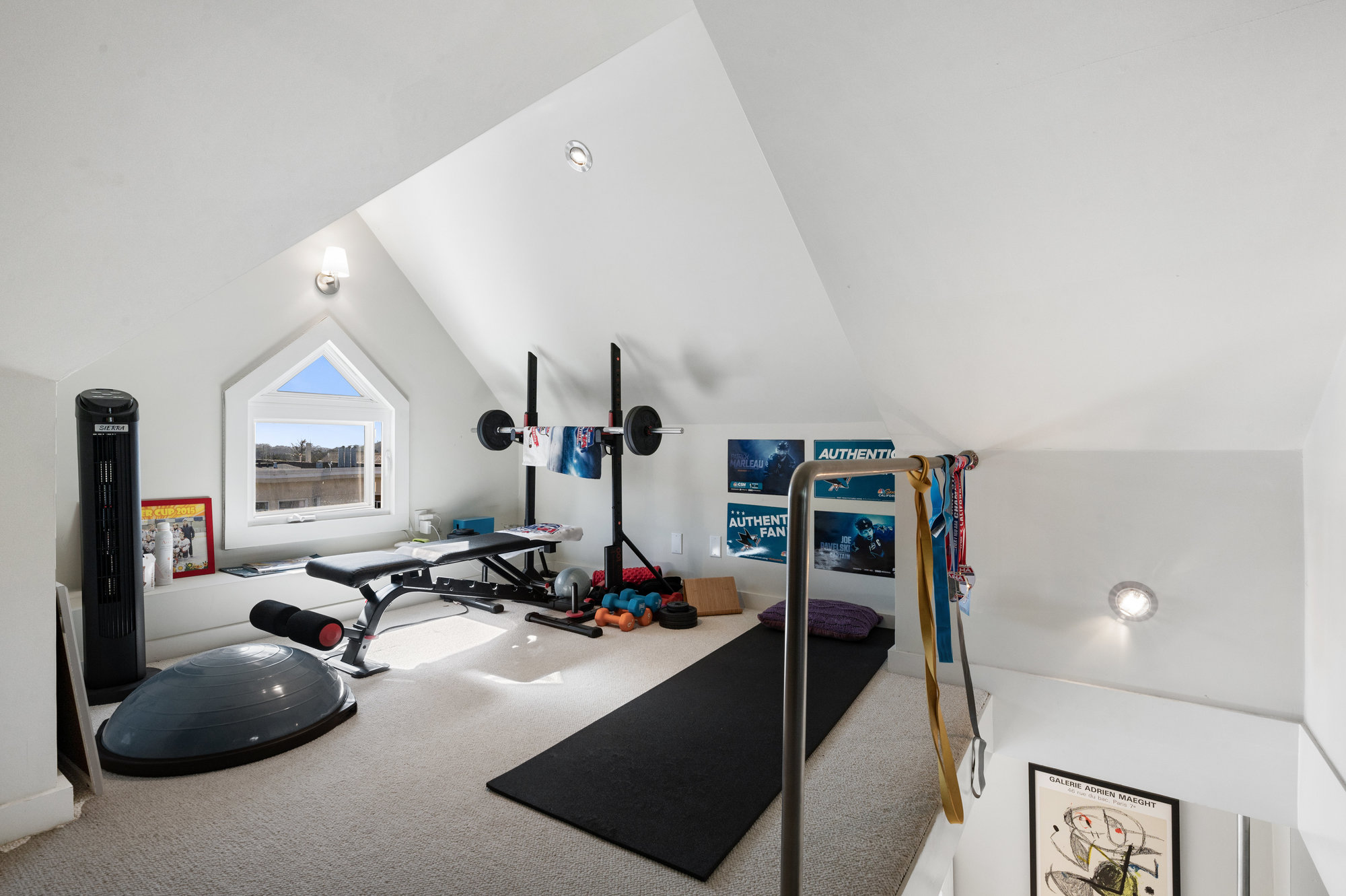 View of the third level, featuring a room with peaked ceilings and a small window