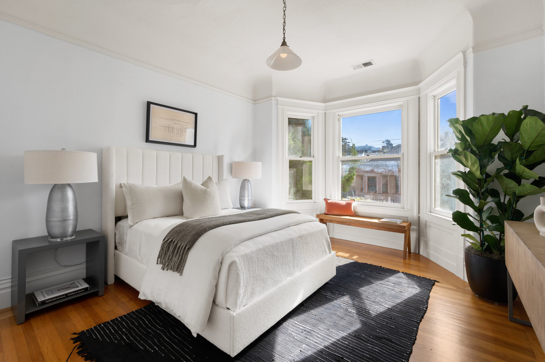 Front guest room has queen bed with two bedside tables.  There is a bench under bay windows and hardwood floors through out.