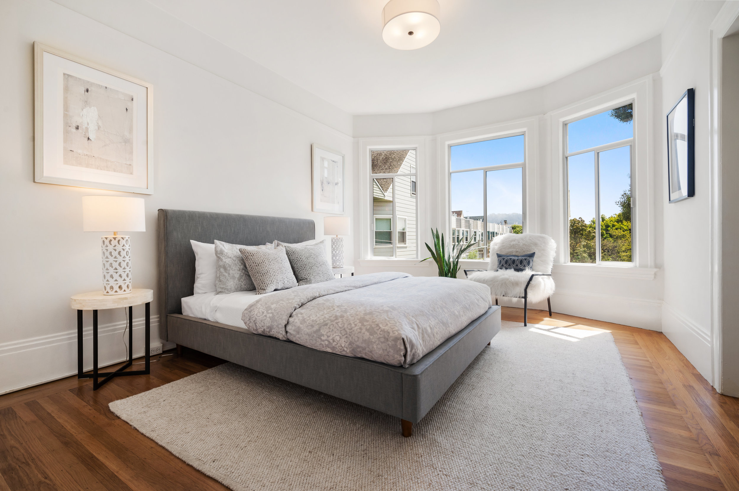 View of a second bedroom with bay windows and wood floors
