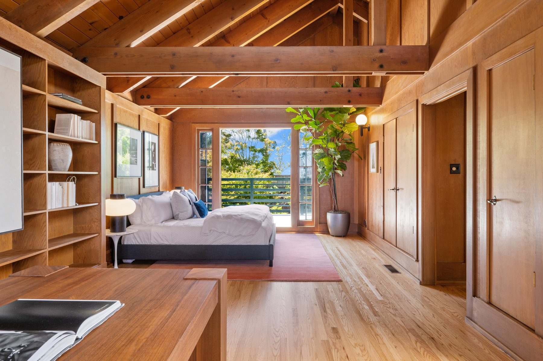 Looking over bedroom area to french doors that open up to deck that looks over back yard.