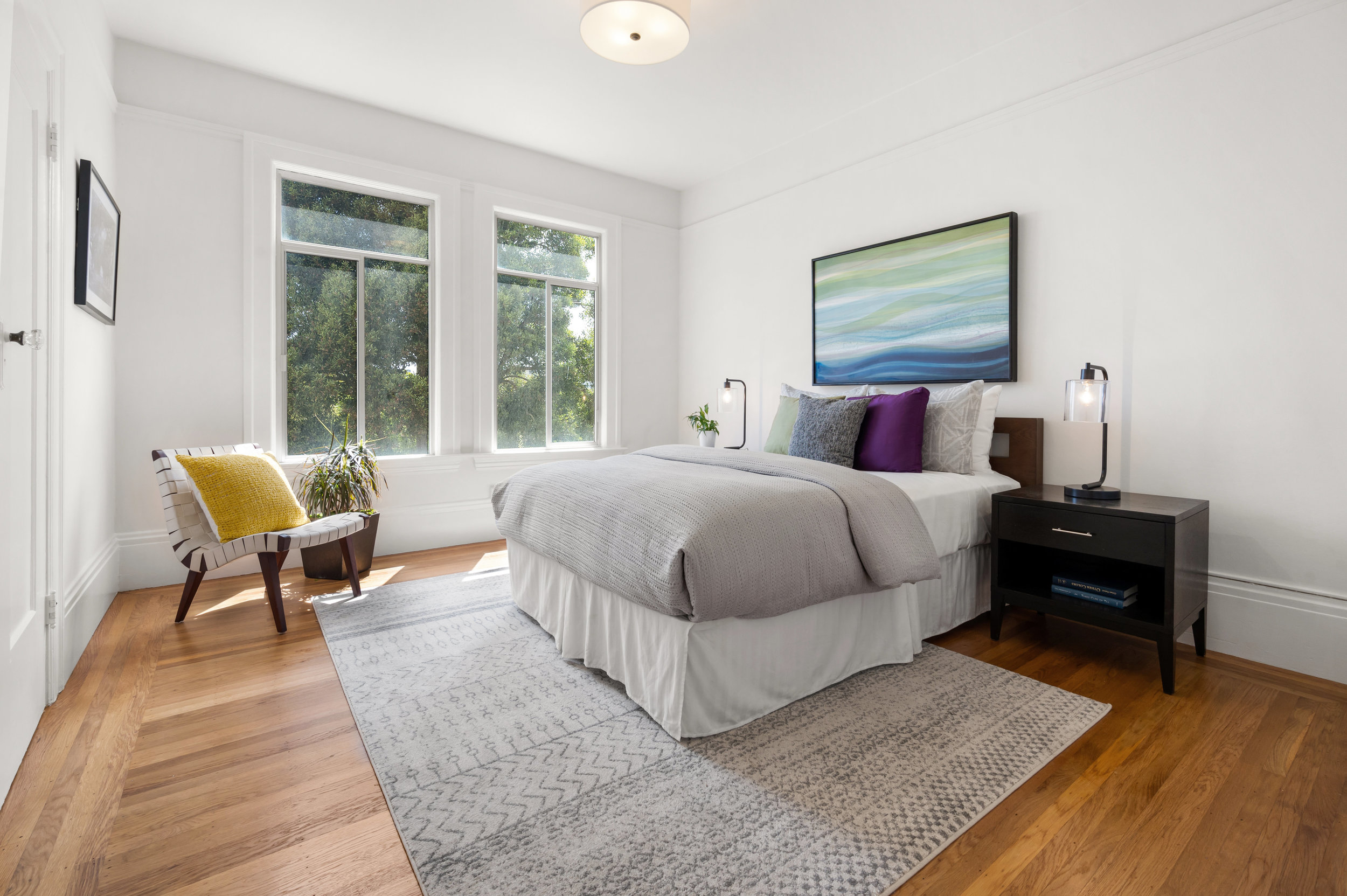 Bedroom three, featuring wood floors and two large windows