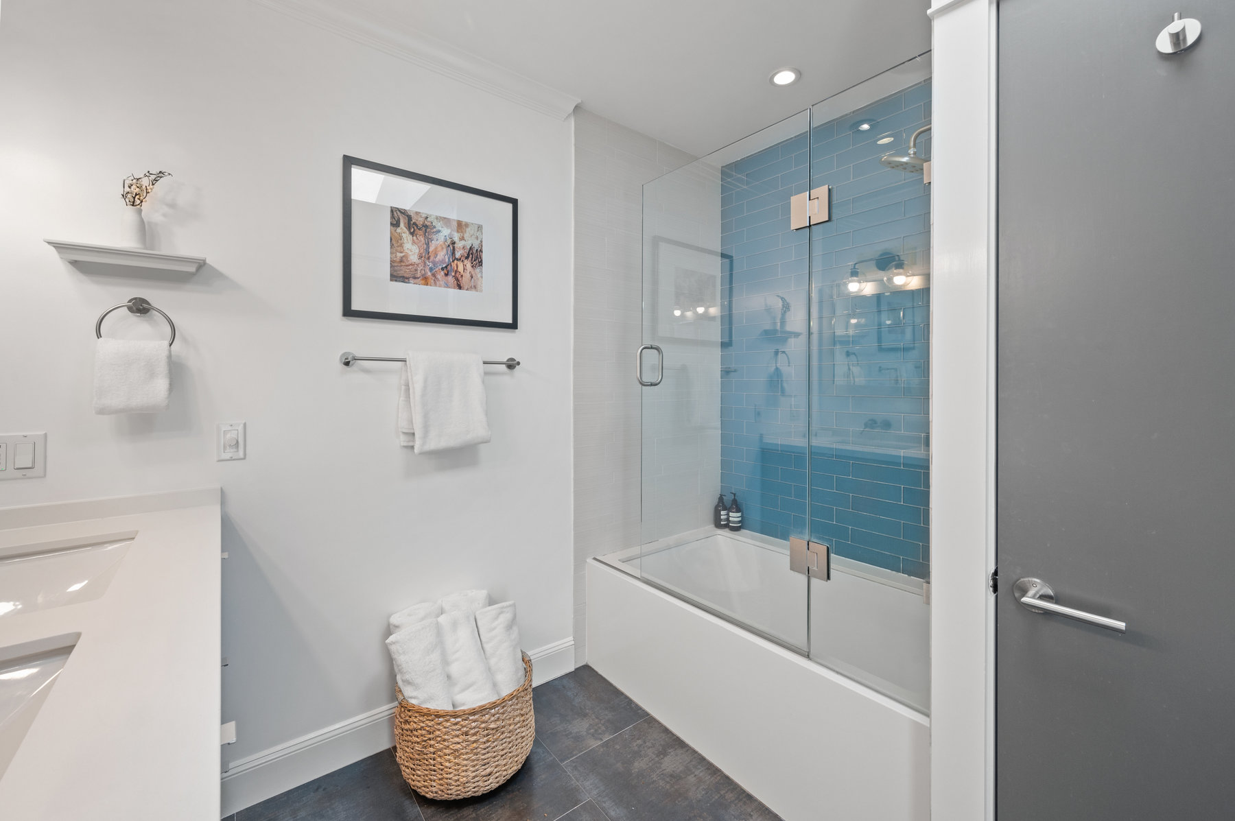 Shower/tub has teal blue glass tile detail.