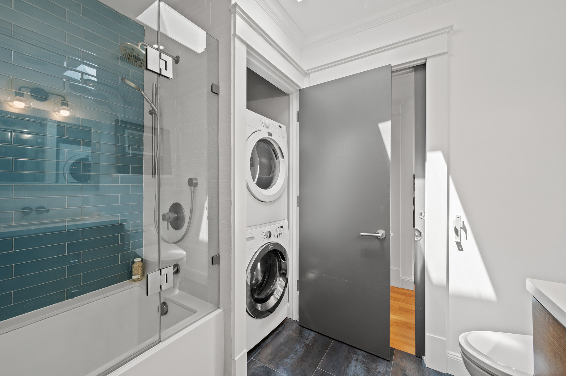 Closet in bathroom has a stacked washer and dryer.