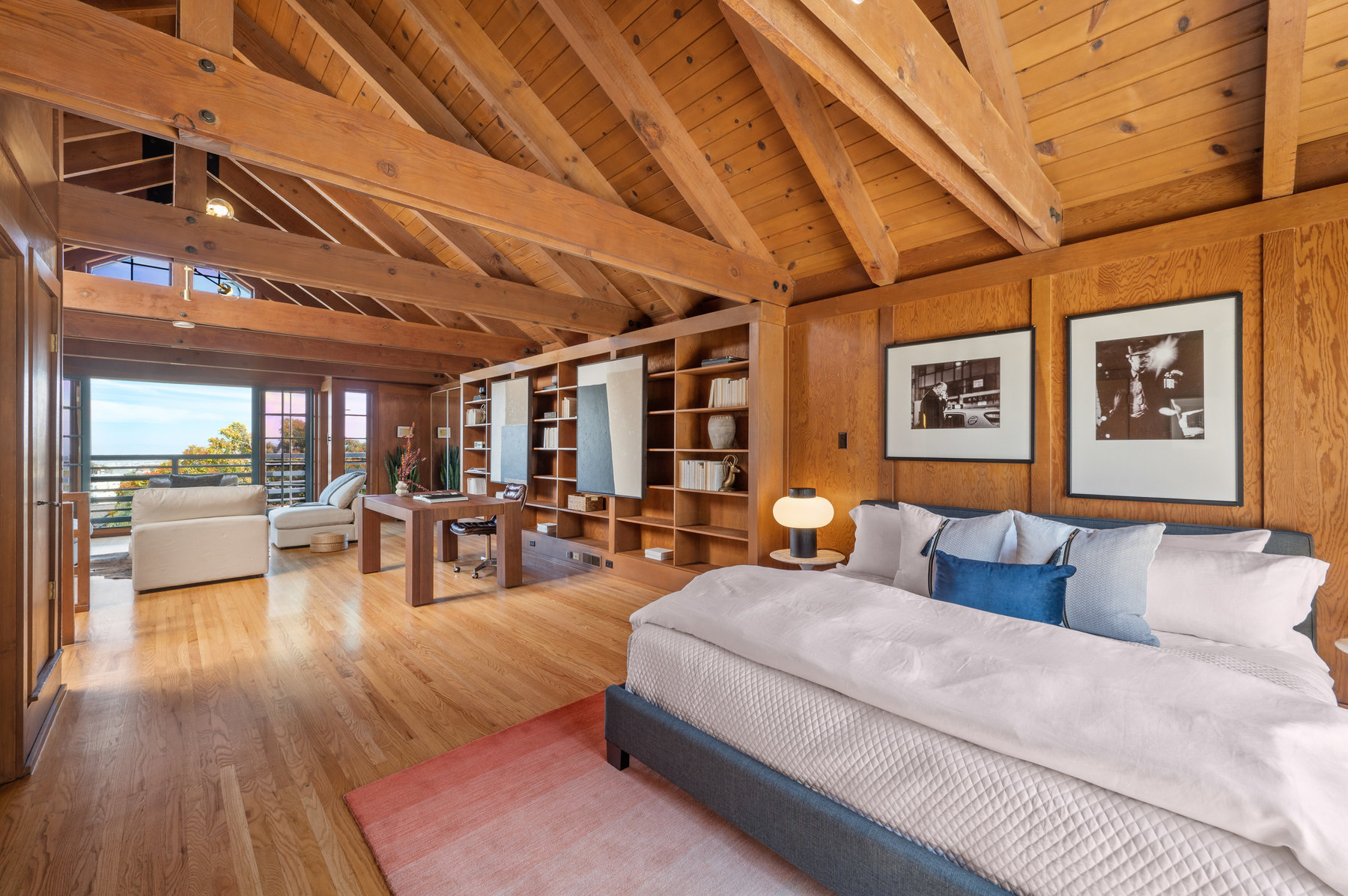 Looking over bedroom to front side of room. There is an office area and sitting area. Very large room filled with wood detailing.