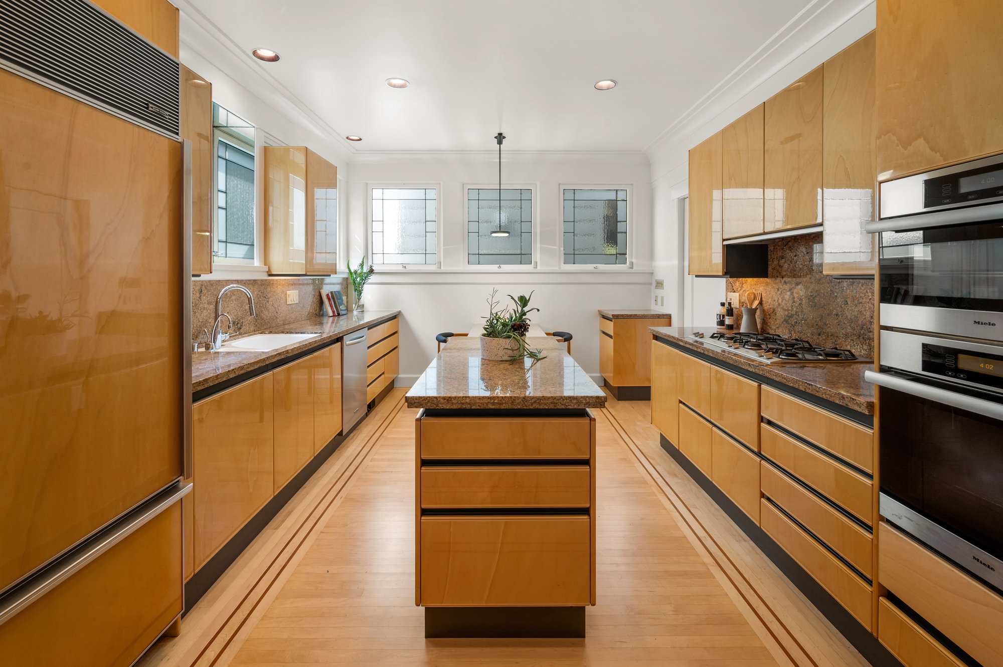 View of the kitchen with sleek wood cabinets and floors