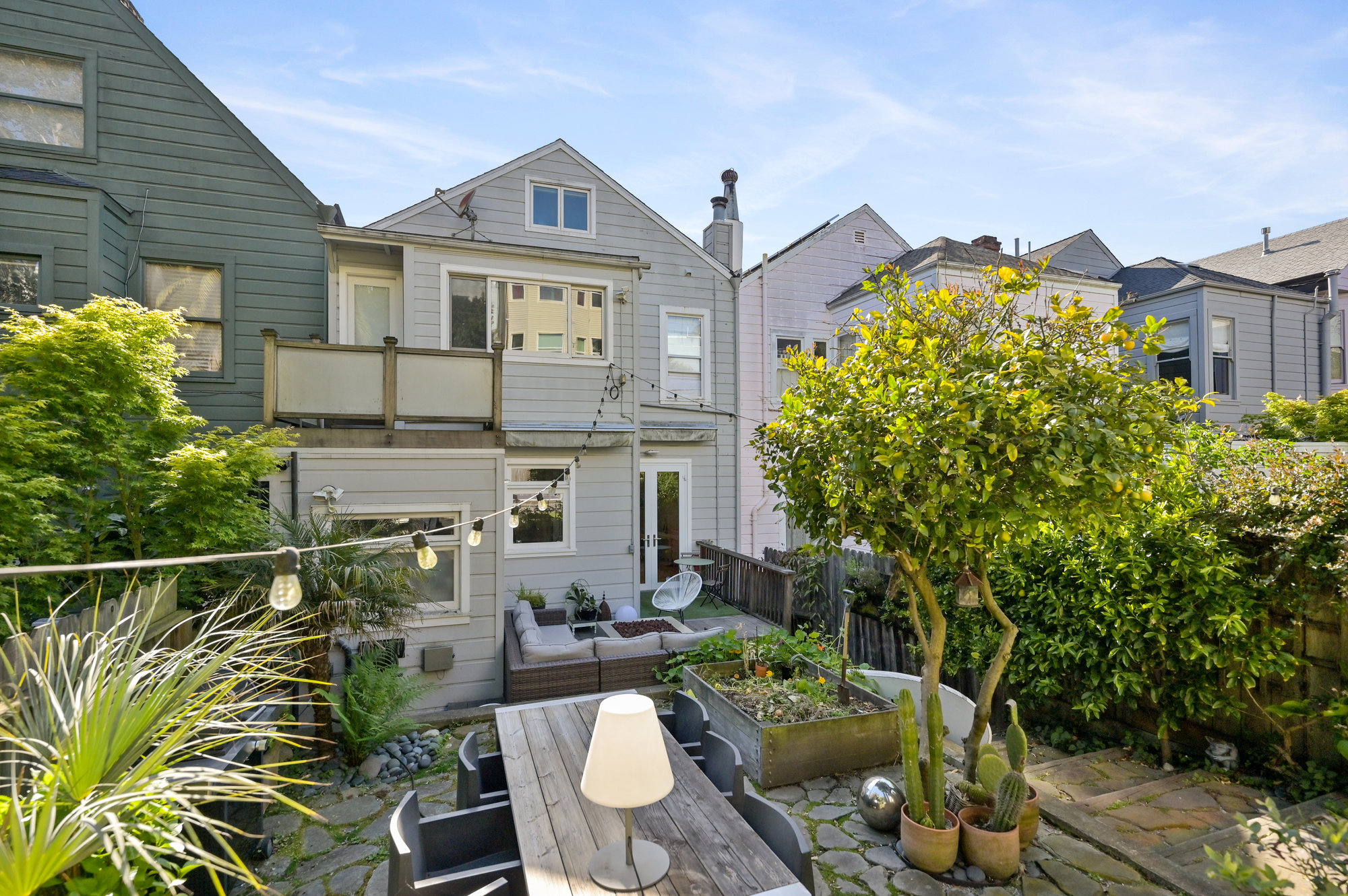 Rear exterior view of 834 Clayton St, showing the large yard and outdoor dining area
