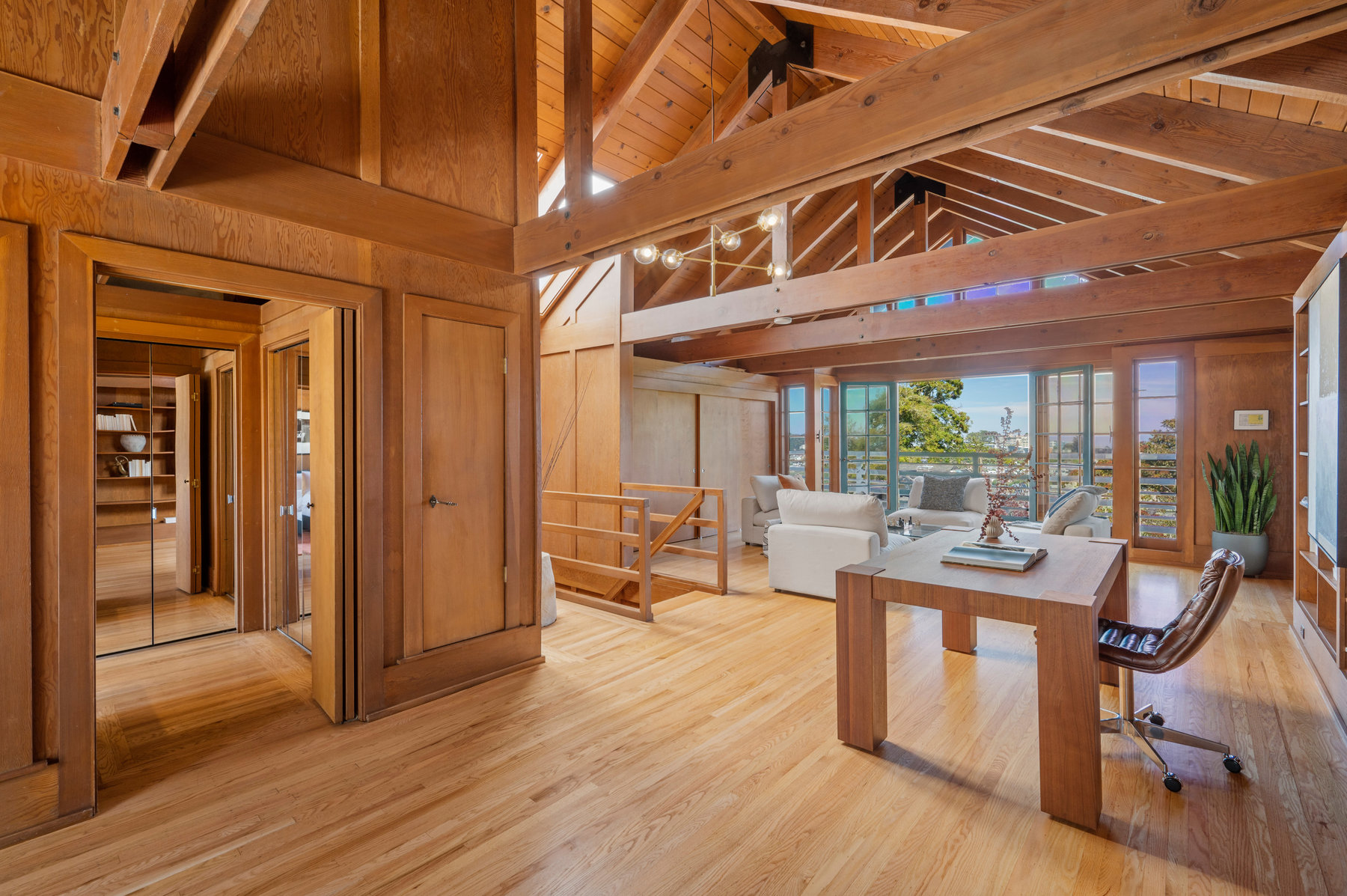 Doorway to the left leads to bathroom, and there is an office area to the right that includes large wooden desk and built it book shelves.