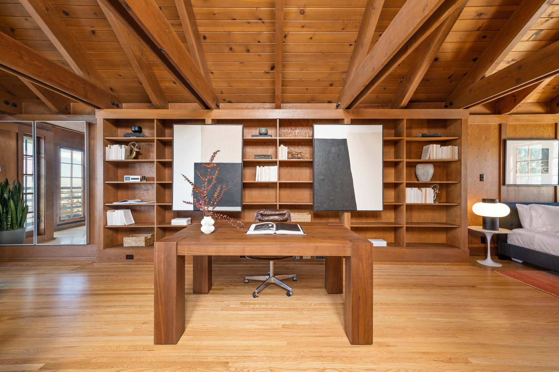 A centered office photo. Large floor to ceiling built in bookshelf fills wall behind desk. Hardwood floors through out.