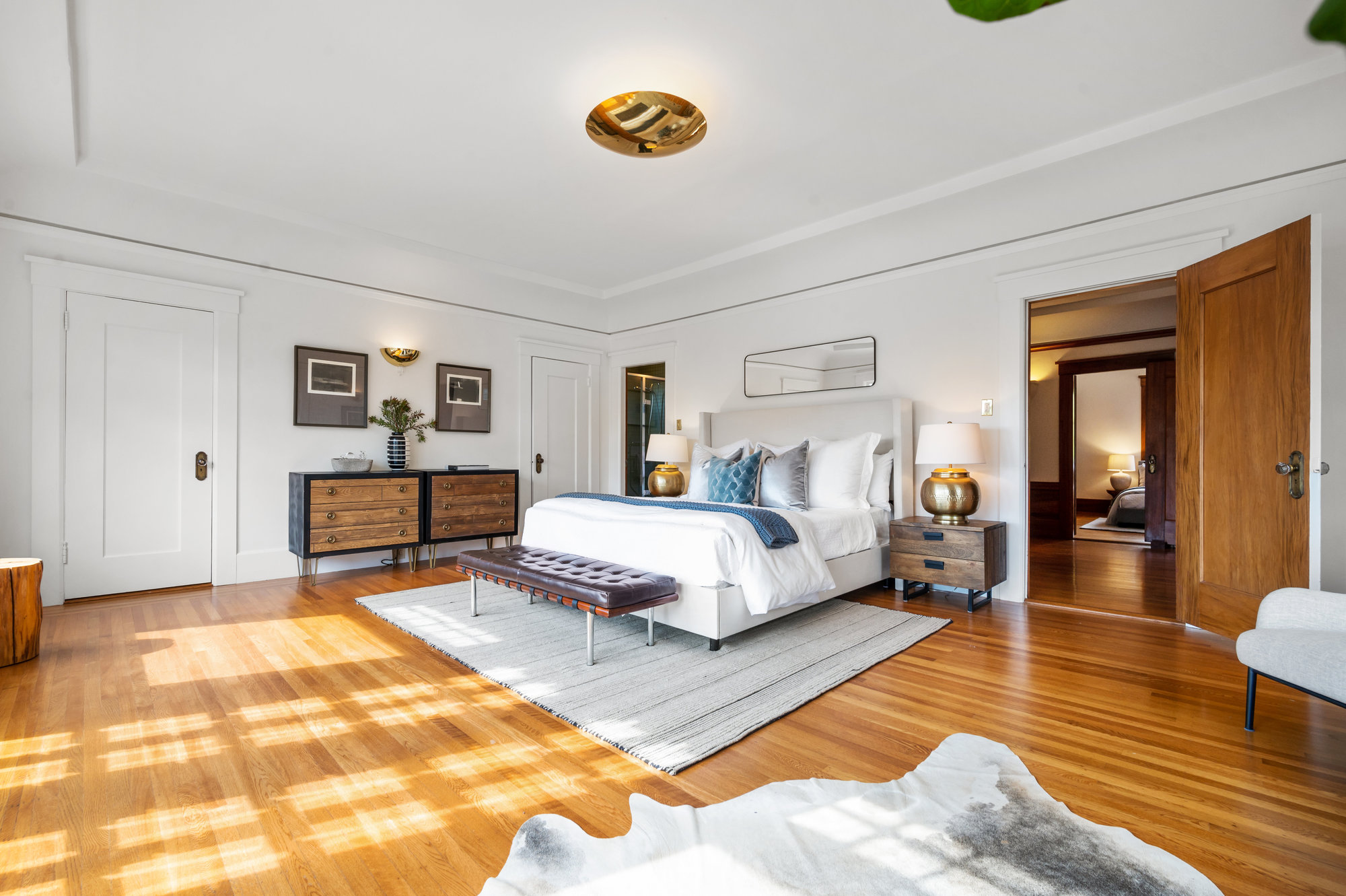 Primary bedroom with light shining across wood floors