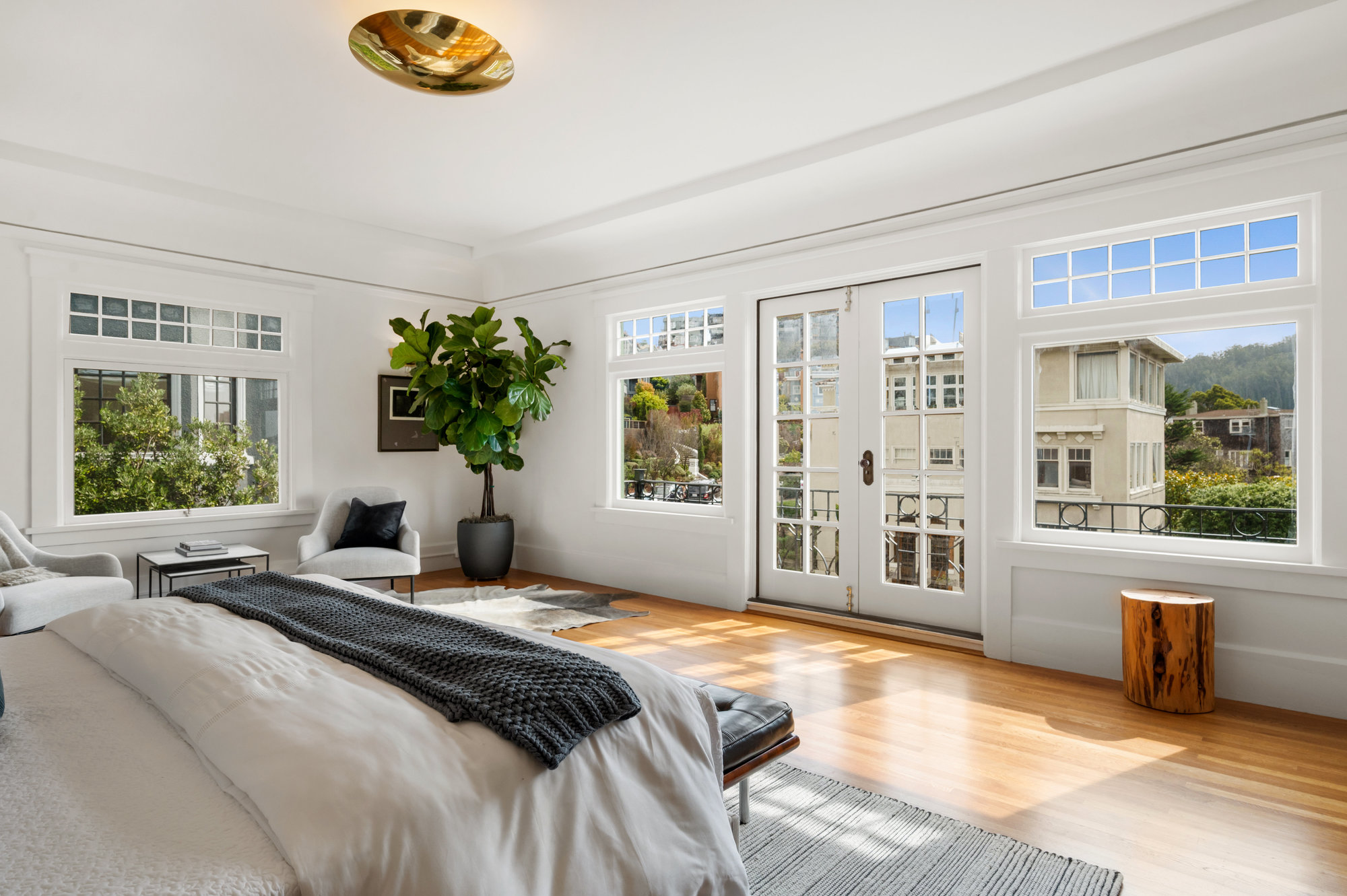 View of the primary bedroom showing large windows with wide white painted frames and French doors leading to a balcony