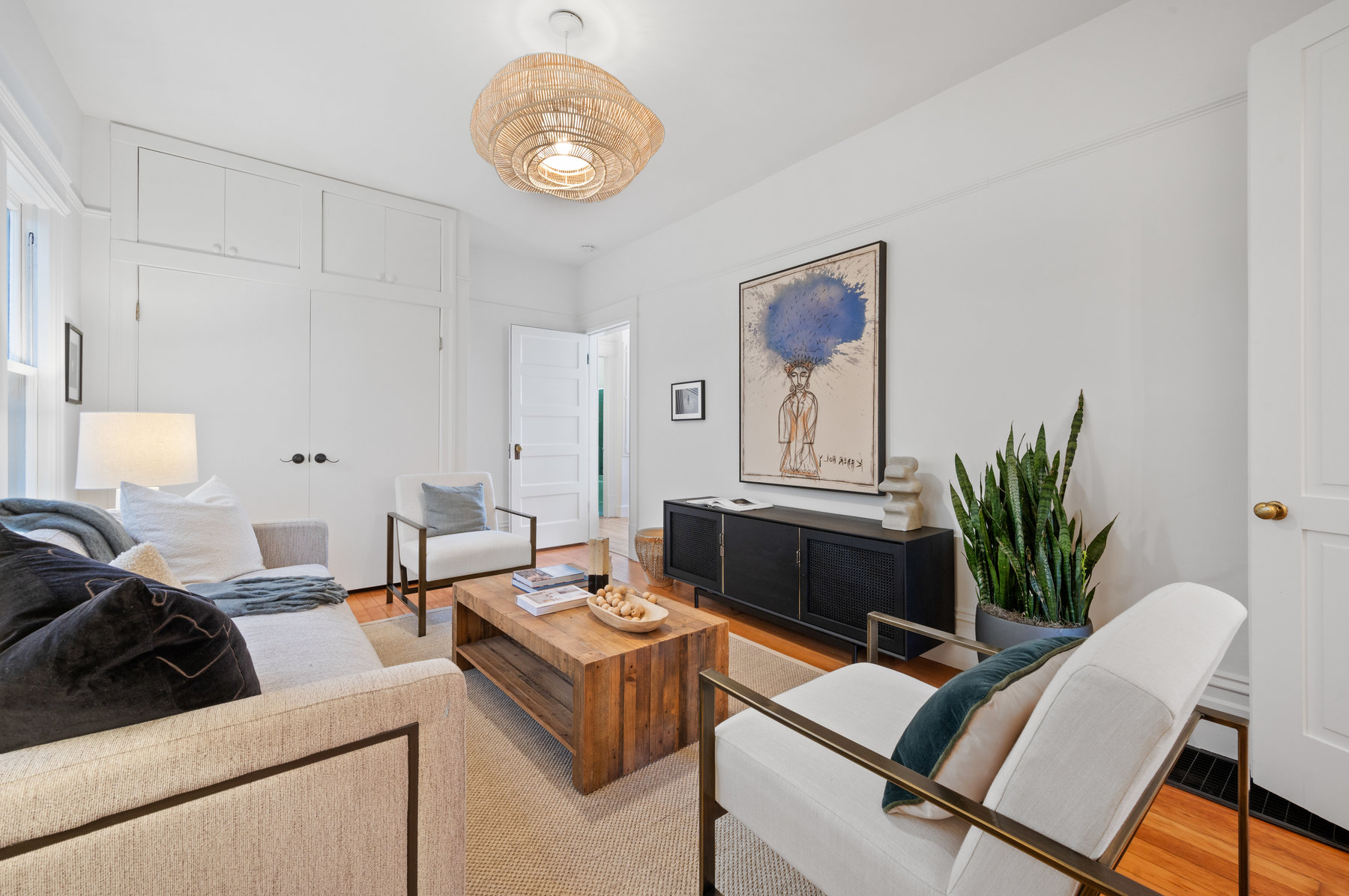 Living room on main floor. White walls and ceiling and hardwood floors throughout.