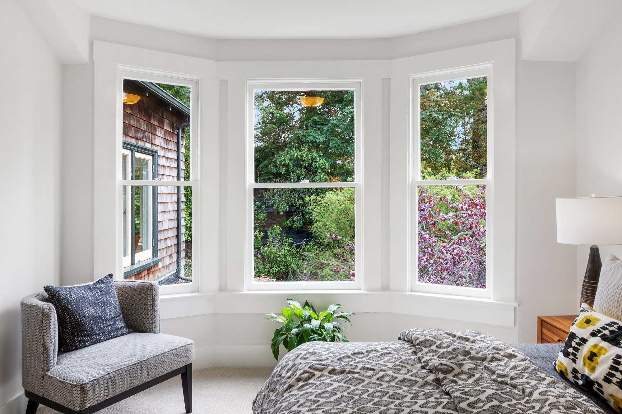 069092 Close-up view of a sitting area and large bay window with a garden beyond