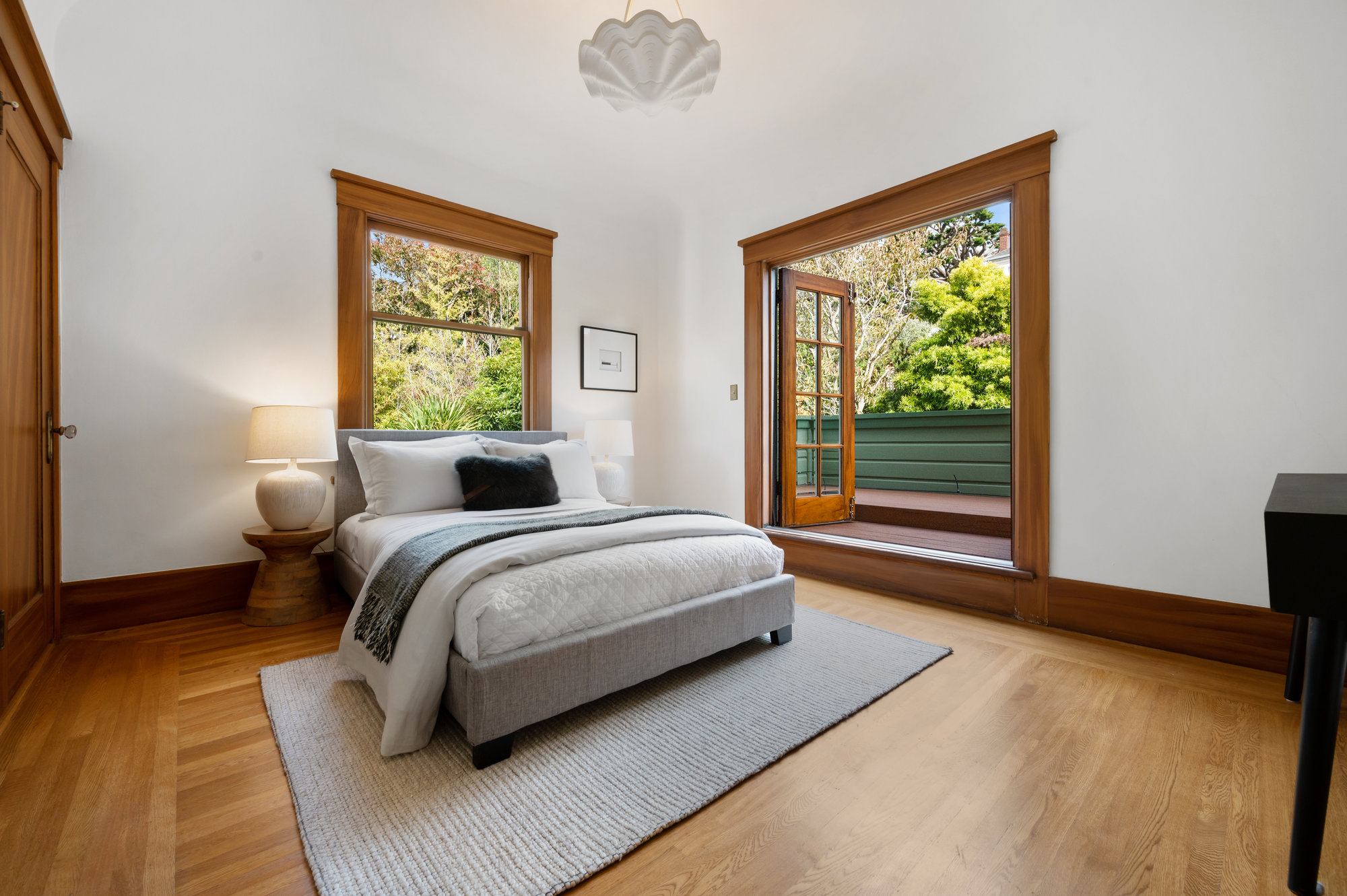 Second bedroom with wood floors and French doors opening to a private balcony