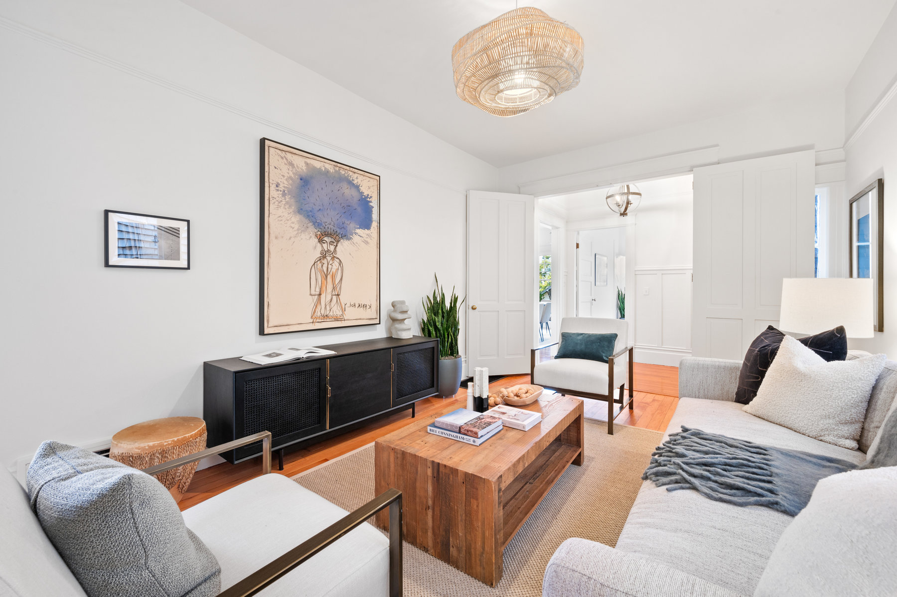 There is a large couch, two sitting chairs, wooden rectangular shaped coffee table, and dresser in living room.