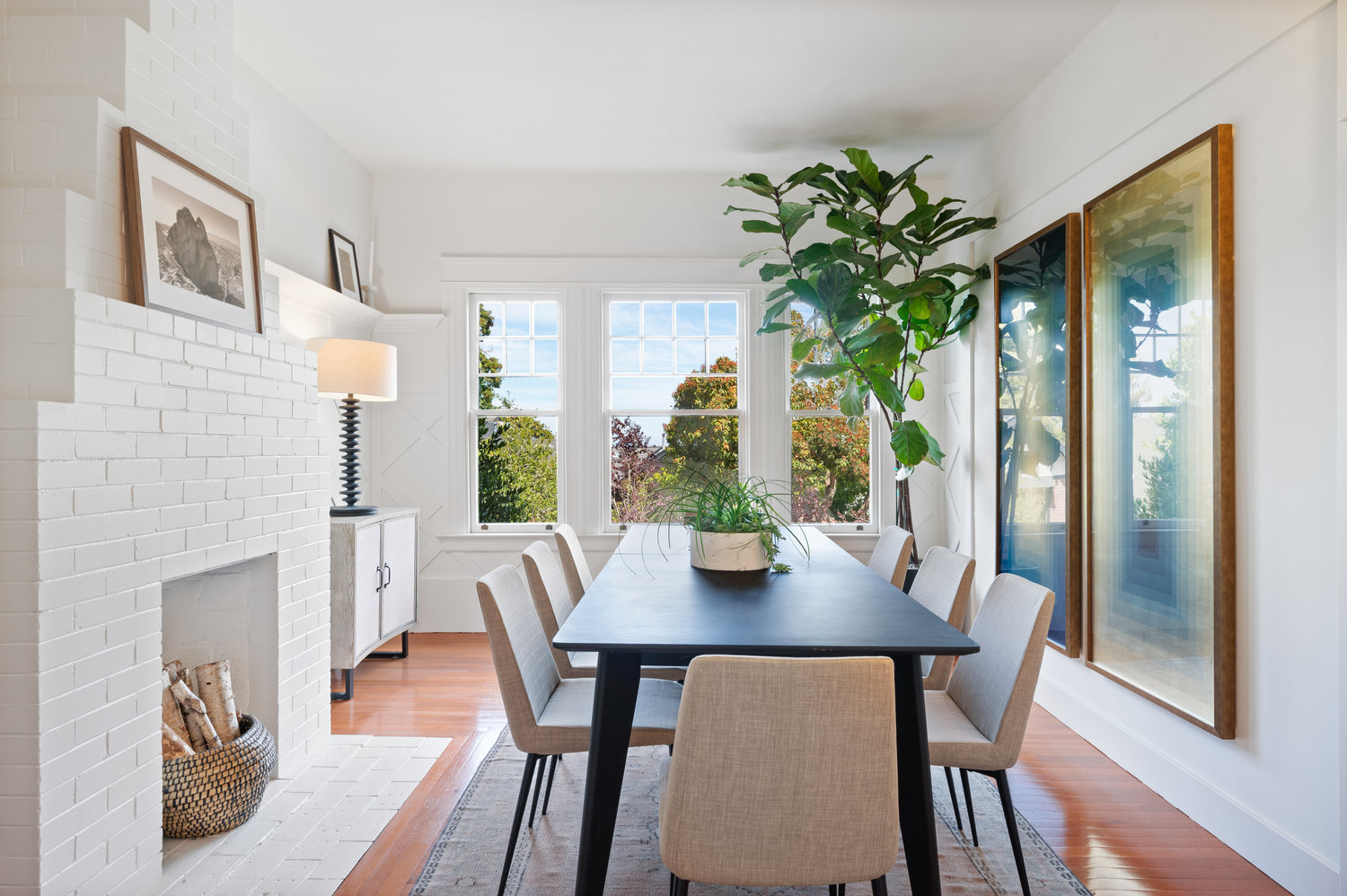 A dining room with fireplace, large windows, and wood floors