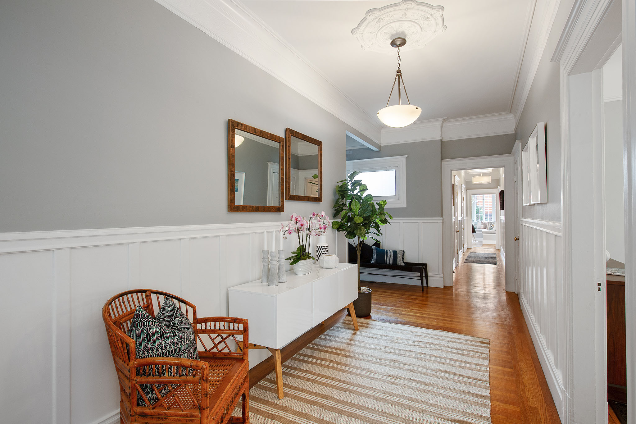 View of the hallway, showing wood floors and white wainscoting