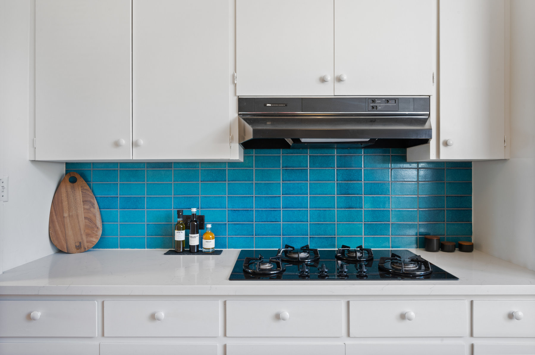 Photo highlights the teal Heath Tile backsplash above the gas stove.