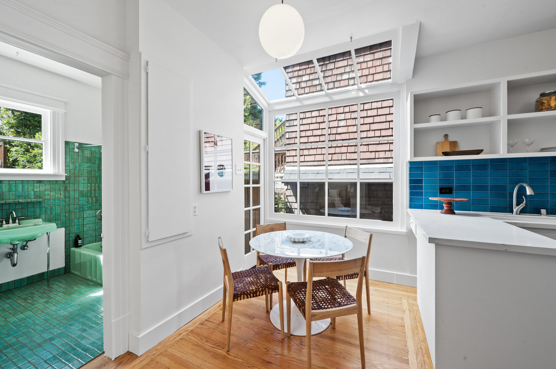 Sitting area in the kitchen has large windows letting in lots of light. To the left in the photo is the guest bathroom.