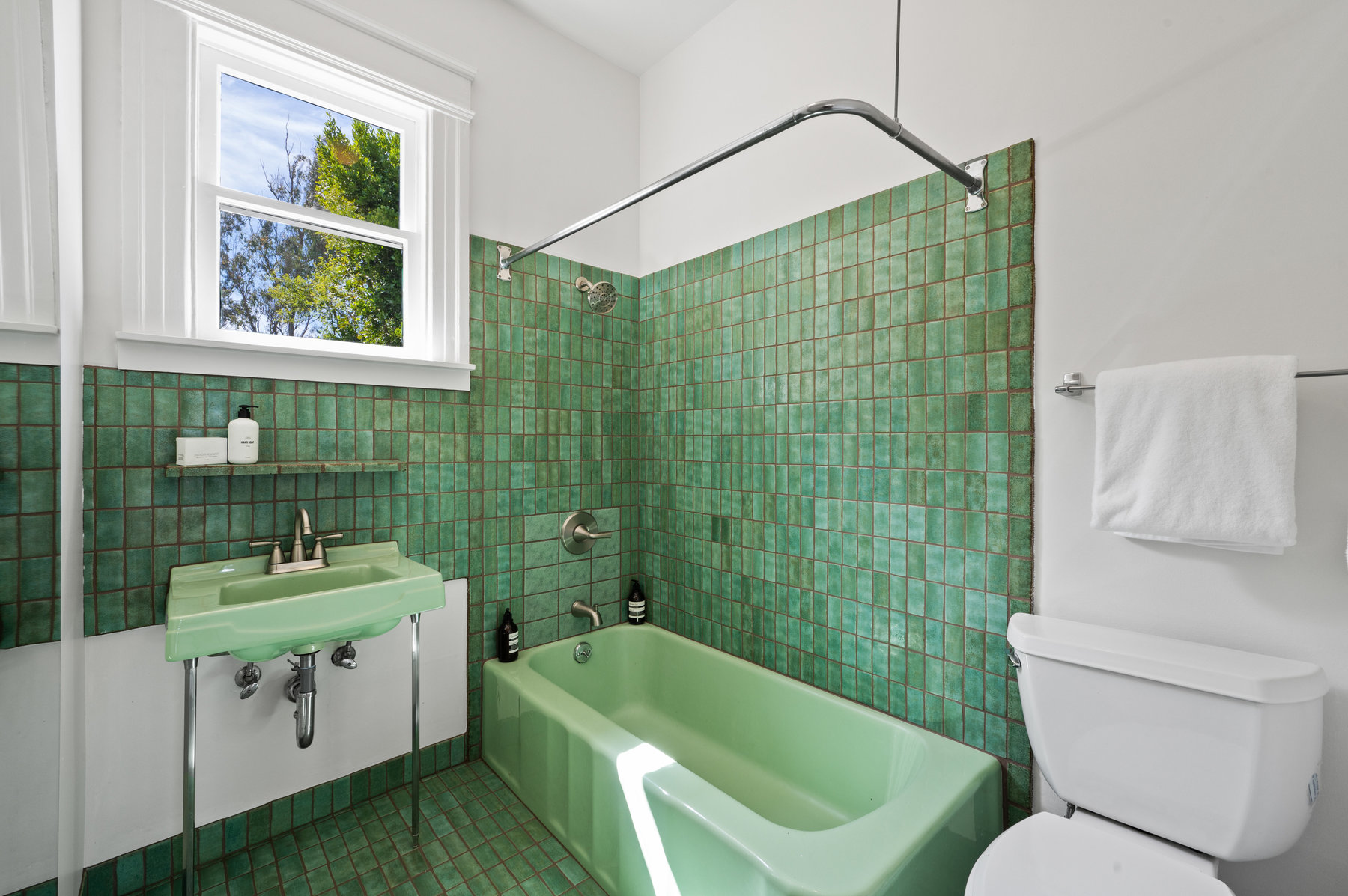 Guest bathroom has green Heath Tile floors and wall around tub and sink.