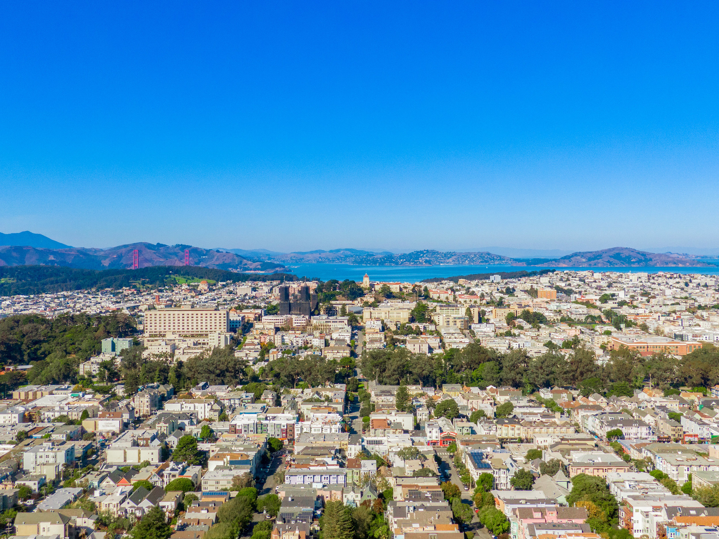 Aerial photo zooming in on bay, Golden Gate Bridge is to left and can see the headlands.