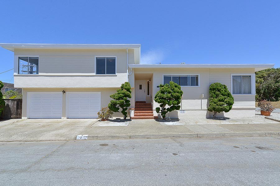 Front exterior view of 1 Country Club Drive, showing cream-colored facade