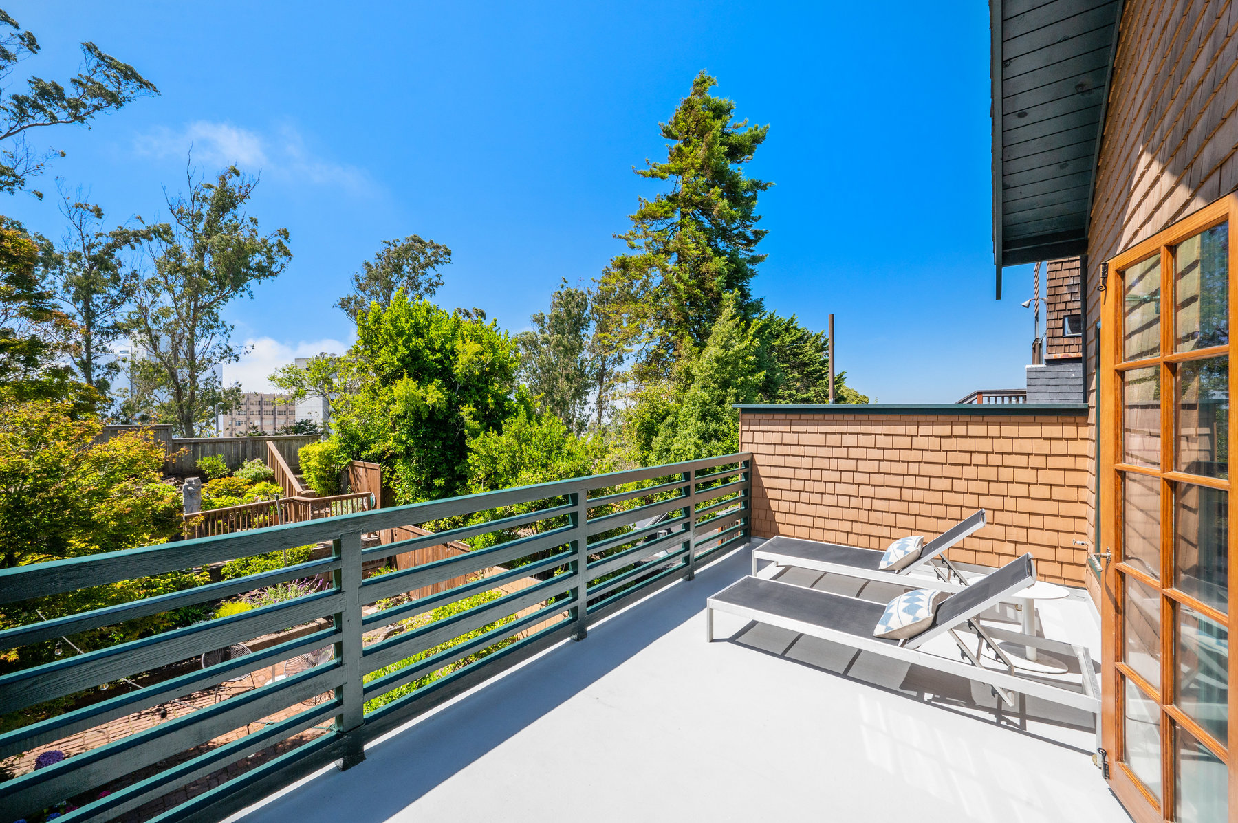 Deck off of the upper room that looks out to the back yard that has lots of greenery.