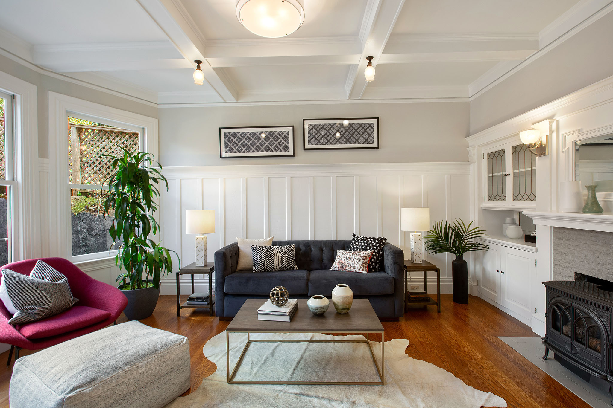 View of the living room, showing boxed ceilings, wood floors and white wainscoting