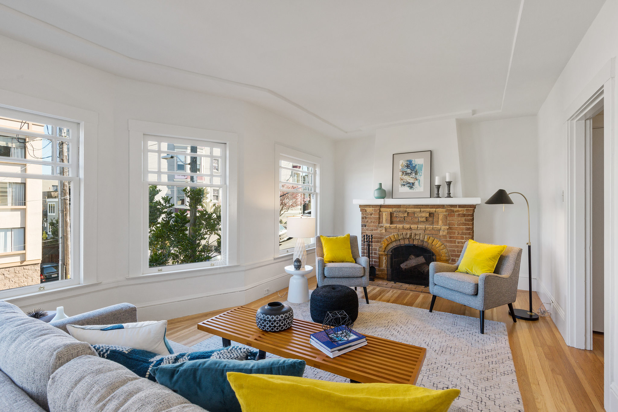 View of the living room, showing a stone fireplace and plenty of natural light