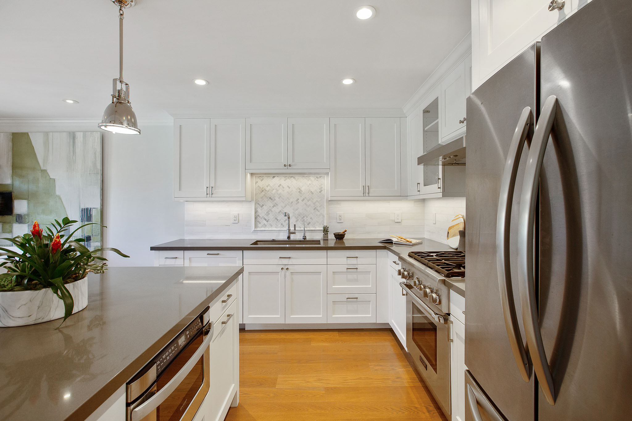 Kitchen has hardwood floors, all stainless appliances with all white cabinetry.