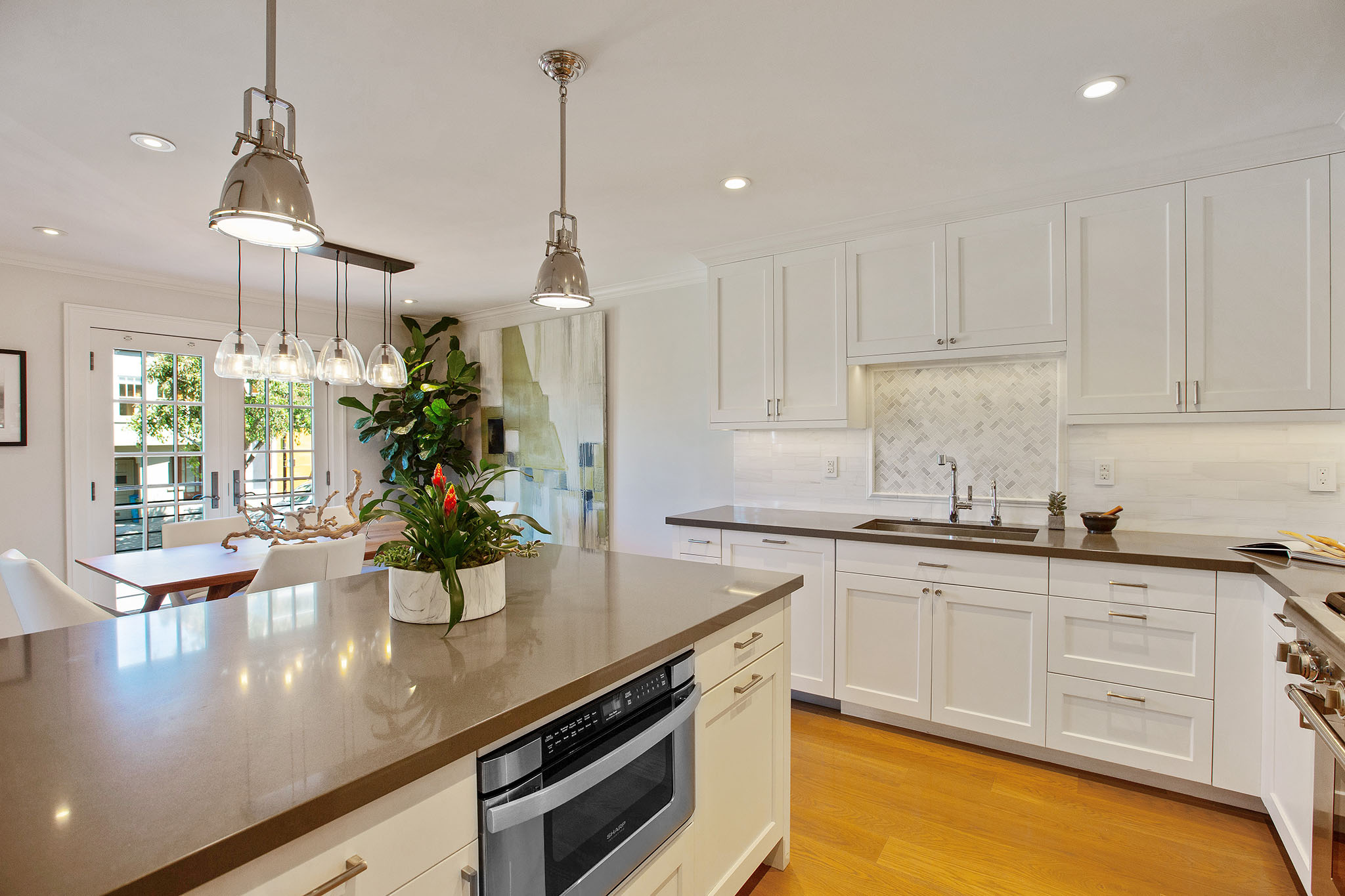 Kitchen has an island that has stone counter top with built in microwave.