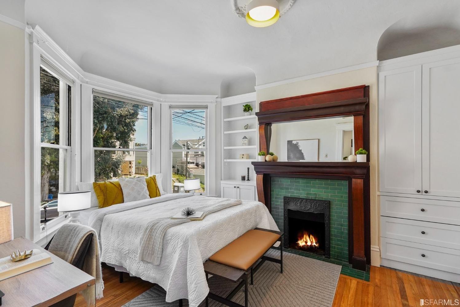 View of the primary bedroom, featuring a large fireplace and bay window