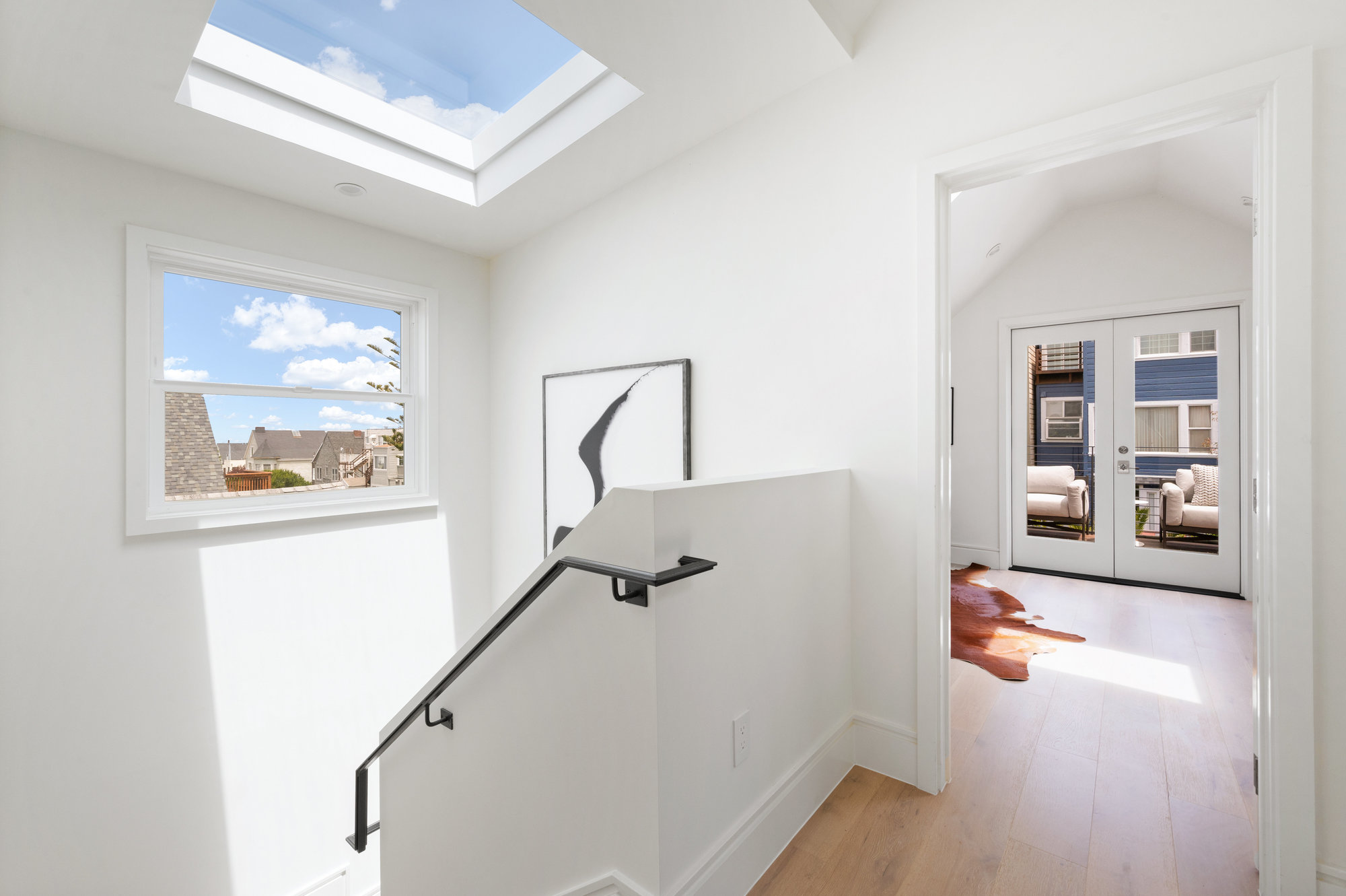 At top of staircase going to upper level there is a skylight and window.