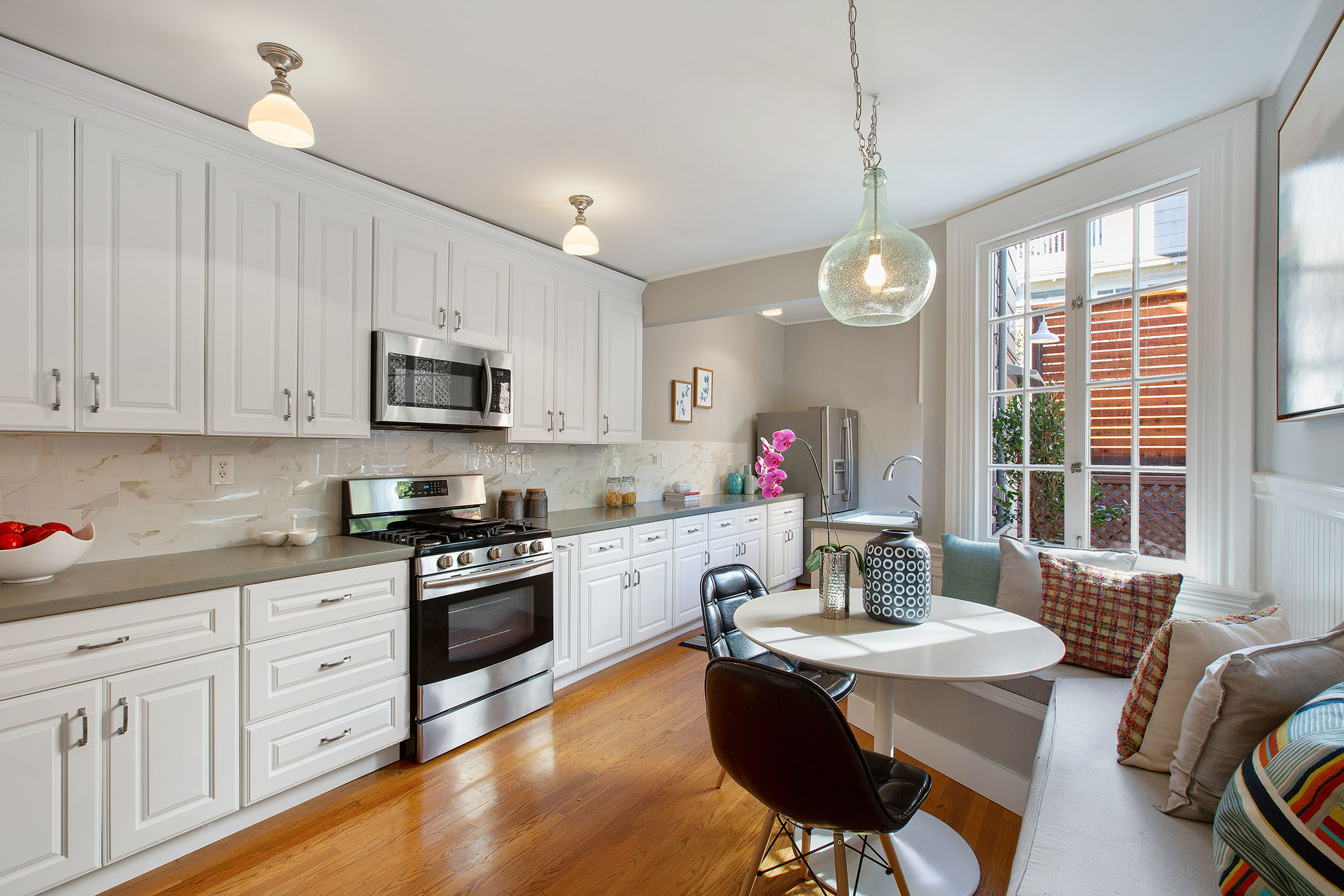 View of the kitchen, featuring a long row of white cabinets and wood floors