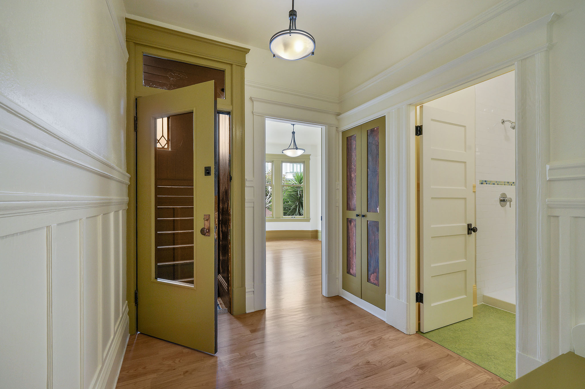 Interior hallway view, showing a peek into a living room and bathroom