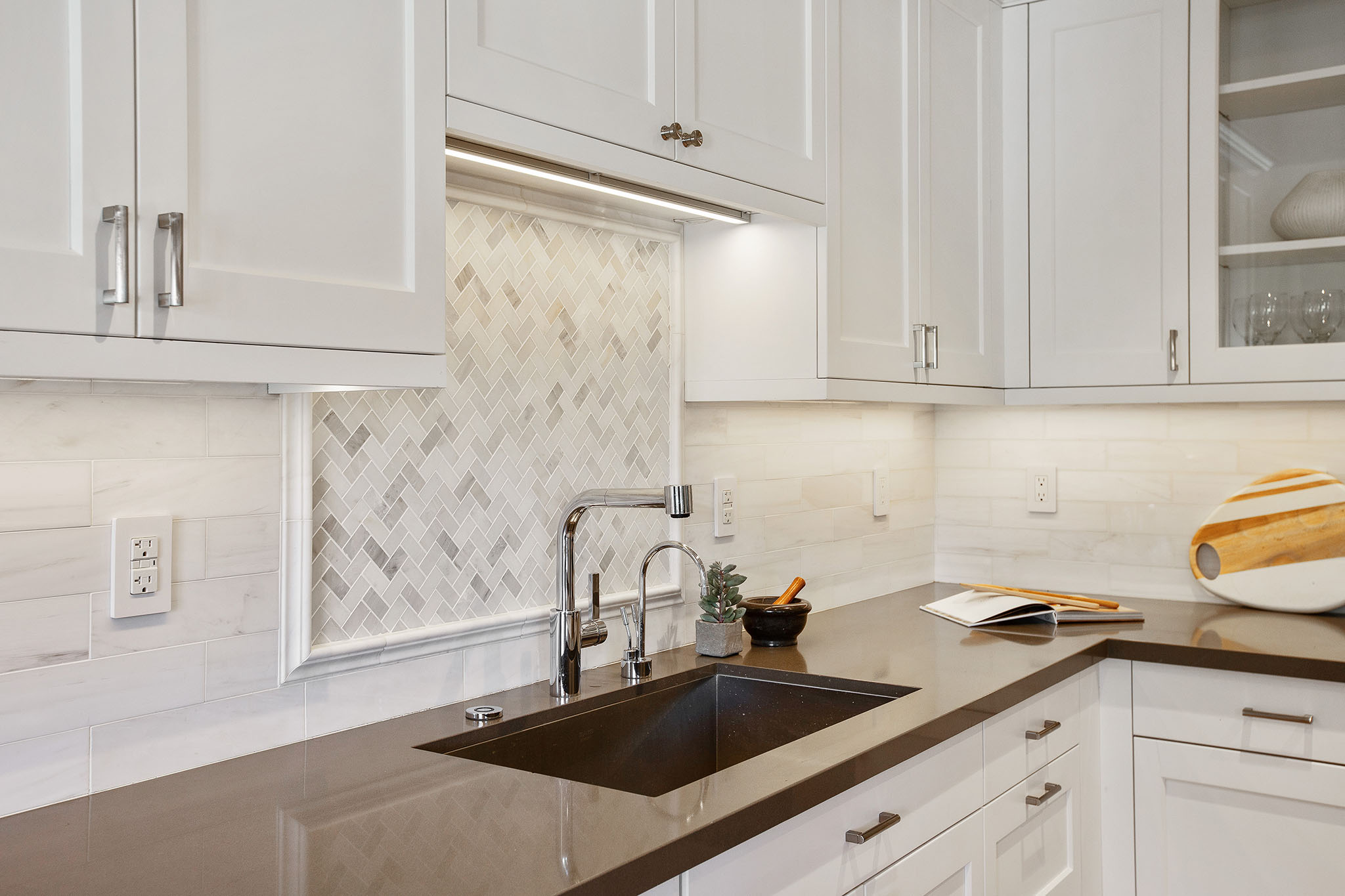 Kitchen sink has chevron tile detail backsplash.