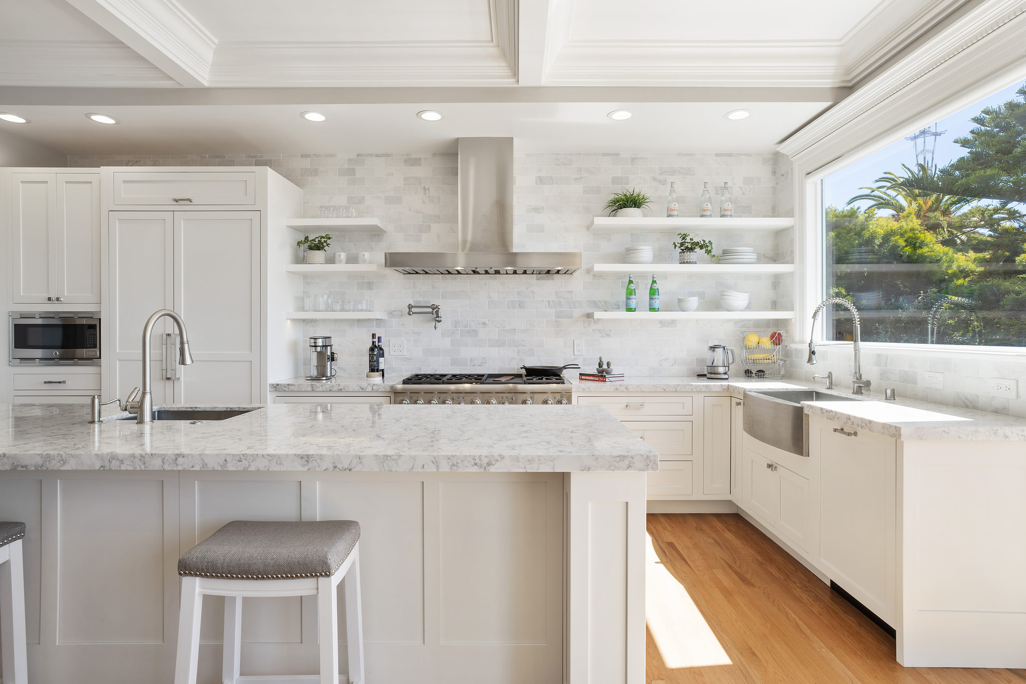 View of the kitchen, featuring luxurious white cabinetry, island, and a large window over the sink