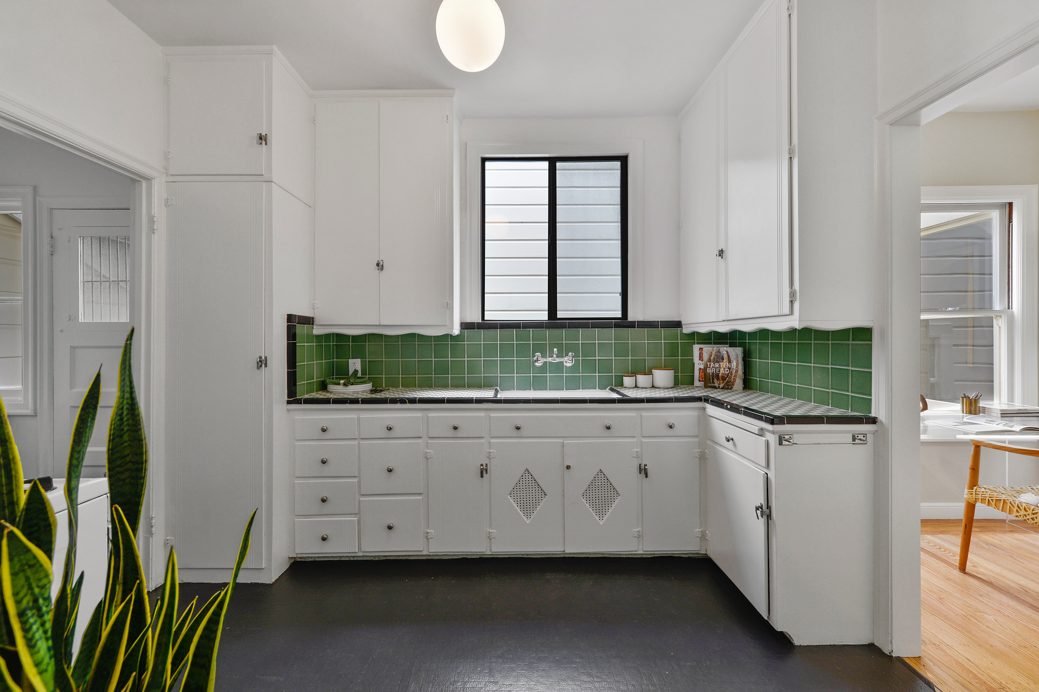 Kitchen with green tile backsplash and white cabinets